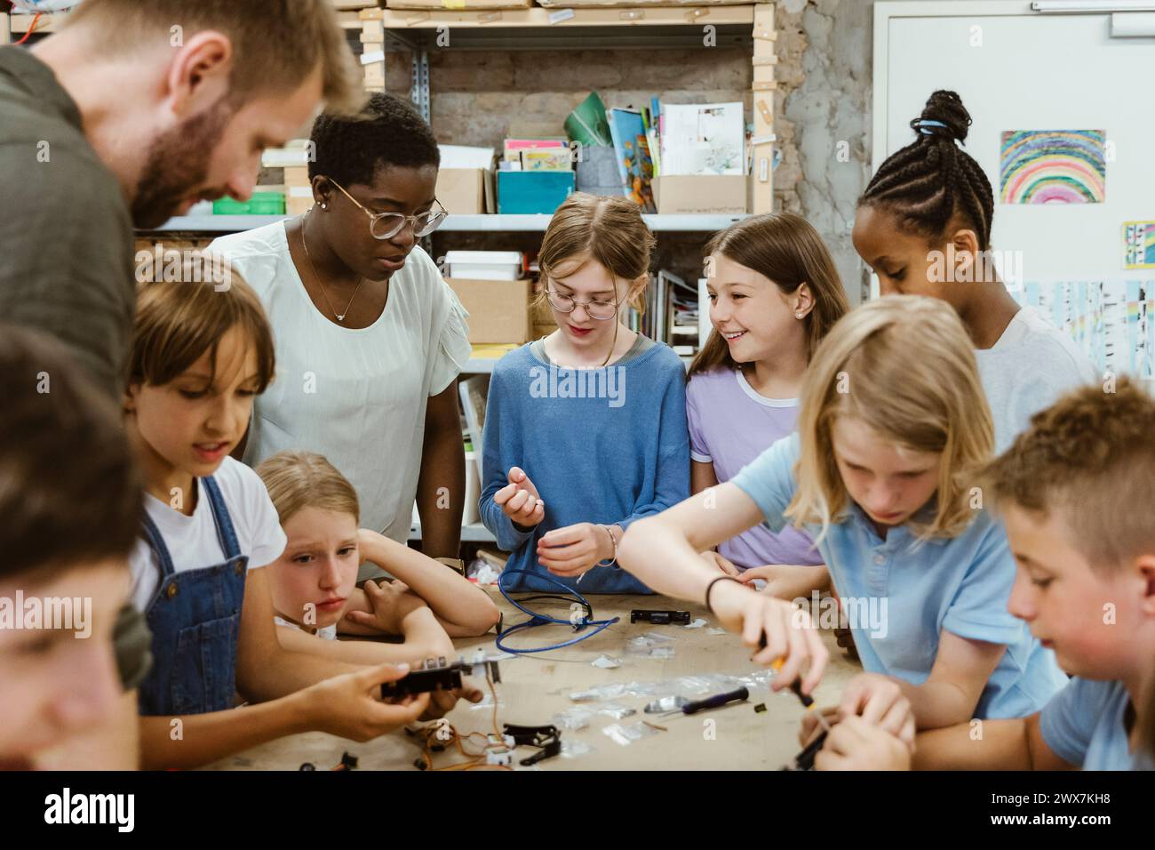Gruppe von Schülern und Lehrern, die sich gegenseitig bei der Arbeit an Robotik-Projekten im Workshop in der Schule unterstützen Stockfoto
