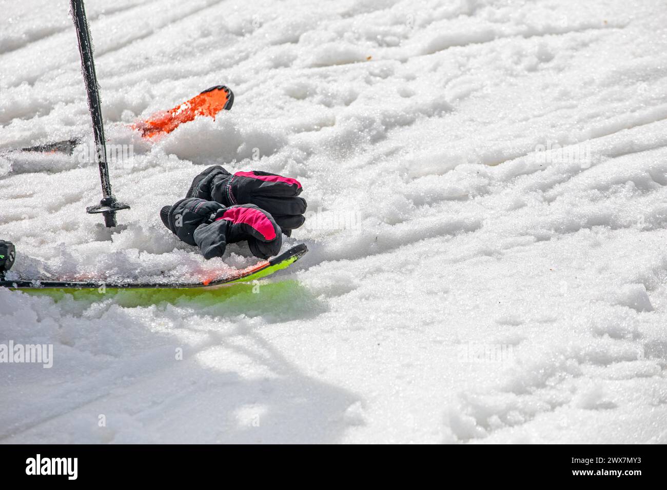 Skier mit Handschuhen auf nassem losen Schnee auf einer Piste an einem sonnigen Tag. Freizeit Stockfoto