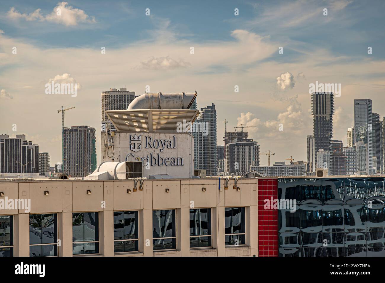 Miami, Florida, USA - 29. Juli 2023: Oberstes Gebäude der Royal Caribbean Group mit Namenslogo im Hafen unter abendlicher Wolkenlandschaft. Die Skyline der Stadt hinten Stockfoto