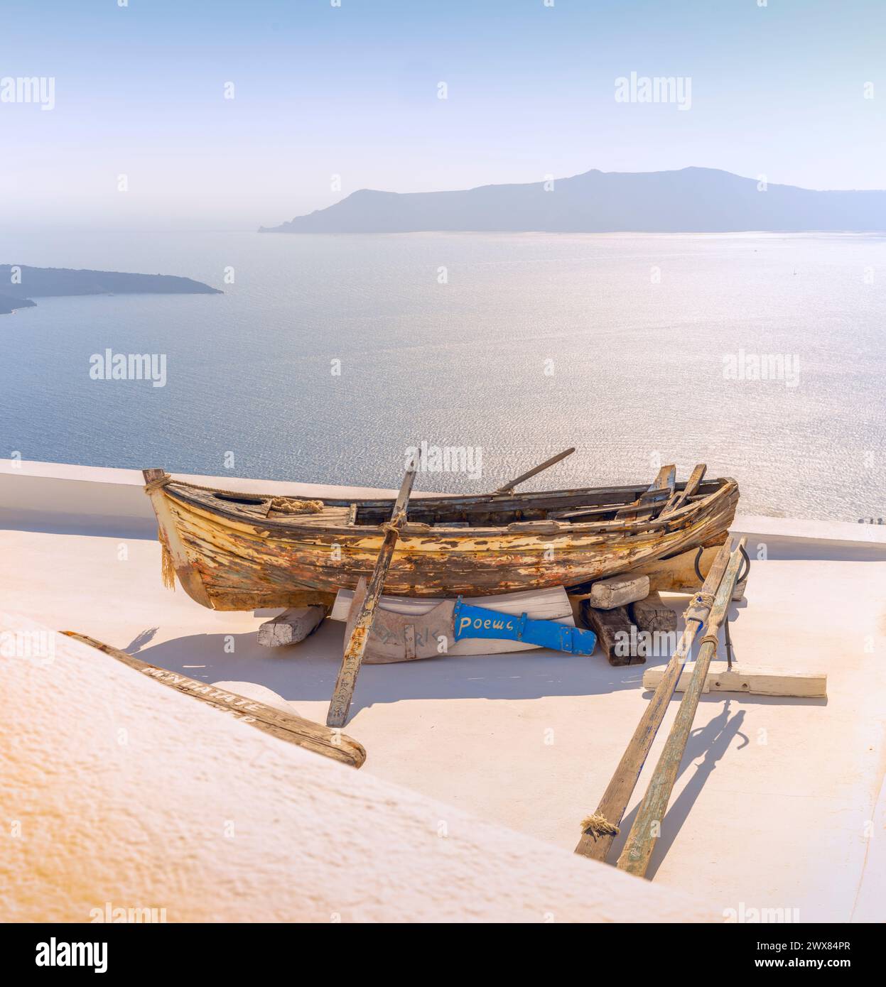 Das schäbige alte Ruderboot wird verwendet, um den Bereich vor einer Wohnung mit Blick auf die Caldera Santorin und die Ägäis zu dekorieren Stockfoto