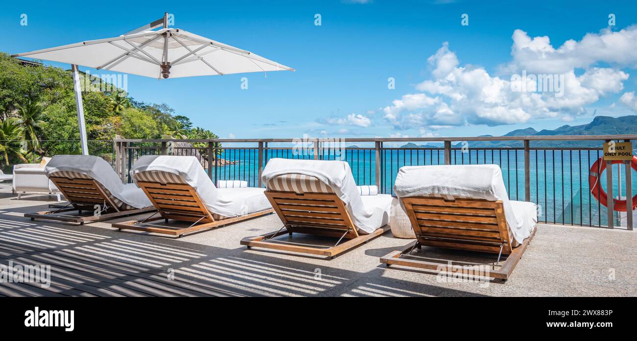 Relax- und Sommerurlaubskonzept: Luxuriöse Liegestühle am Pool an tropischem Ziel. Stockfoto