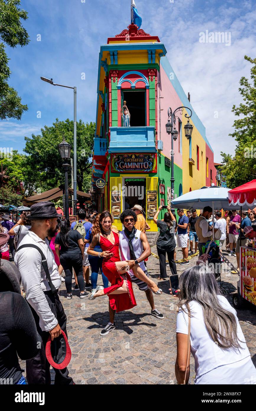 Touristen posieren für Fotos vor Einem farbenfrohen Gebäude im Viertel La Boca in Buenos Aires, Argentinien. Stockfoto
