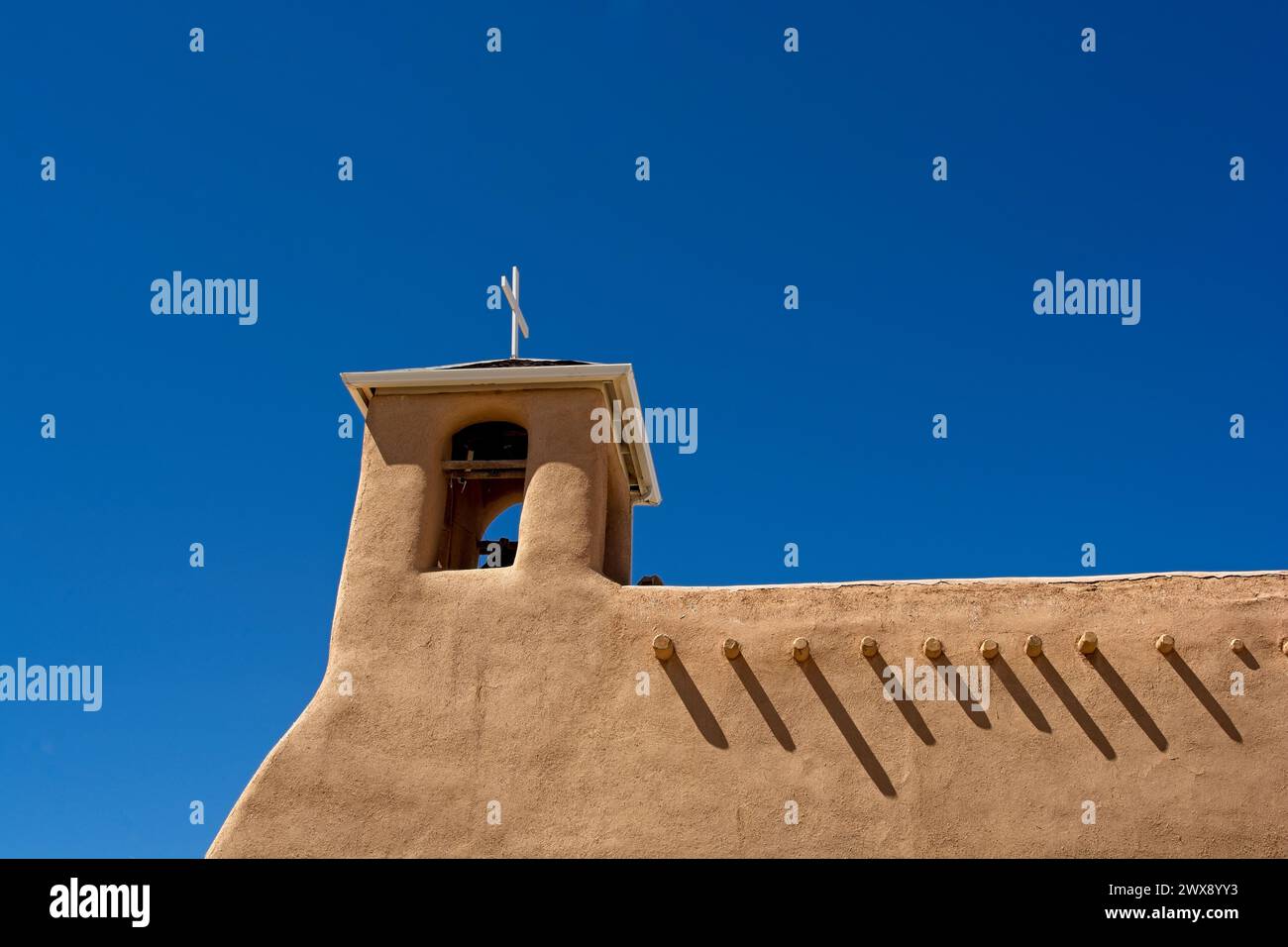 Lehmwände und Glockenturm mit freiliegenden Viga-Dachbalken der San Francisco de Assisi Missionskirche in Taos, New Mexico Stockfoto