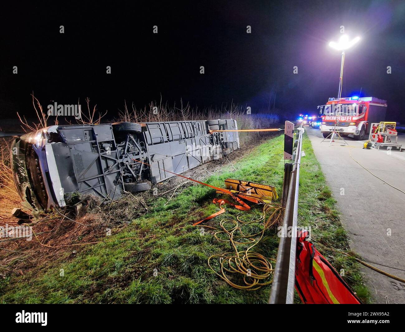 29. März 2024, Nordrhein-Westfalen, Werl: Ein Bus liegt nach einem Unfall auf seiner Seite an der Autobahn A44. Ein mit rund 60 Fahrgästen beförderter Reisebus hat auf der Autobahn A44 in Nordrhein-Westfalen die Straße verlassen und ist auf die Seite gestürzt. Nach aktuellen Informationen war es ein Unfall ohne Beteiligung anderer Fahrzeuge und die Ursache ist noch unklar, teilte die Polizei am Freitagabend mit. Zunächst war unklar, ob es bei dem Unfall bei Werl zu Verletzungen kam. Die A44 wurde von der Ausfahrt Unna Ost bis Werl in Richtung Kassel vollständig gesperrt. Zusätzlich zur Feuerwehr Stockfoto