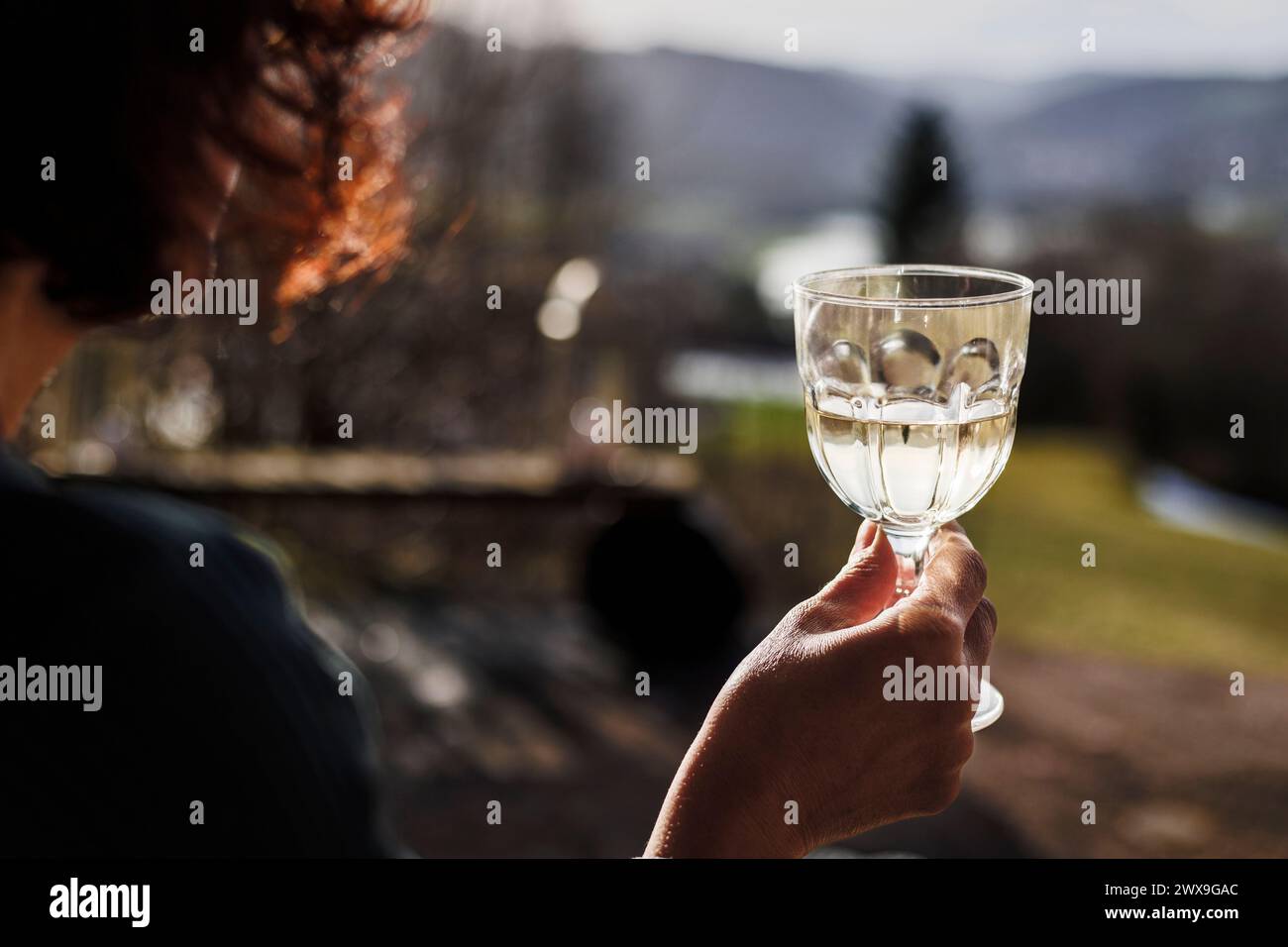 Frau mittleren Alters trinkt Wein während des Sonnenuntergangs Stockfoto