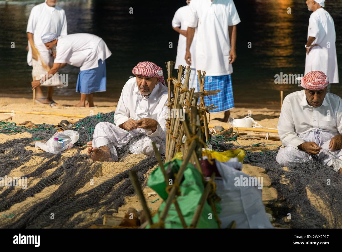 Ein arabischer Mann repariert ein Fischernetz während des Katara International Dhow Festivals am Strand des Kulturdorfes Katara. Stockfoto