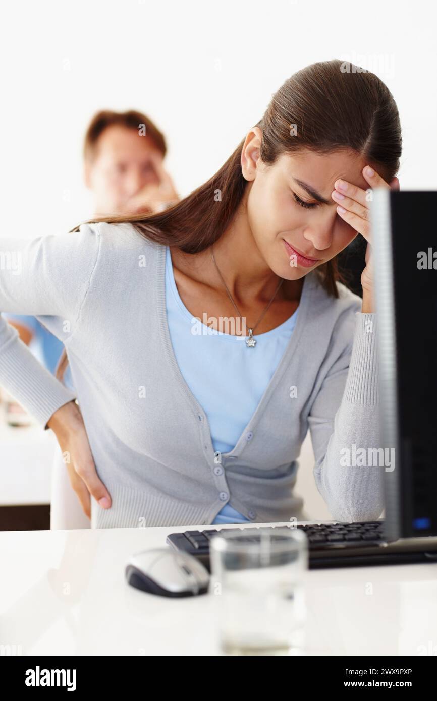 Frau, Rückenschmerzen und Stress im Büro mit Computer am Arbeitsplatz, Migräne oder Kopfschmerzen am Arbeitsplatz. Weibliche Angestellte und Spannung am Schreibtisch im Arbeitszimmer mit Stockfoto