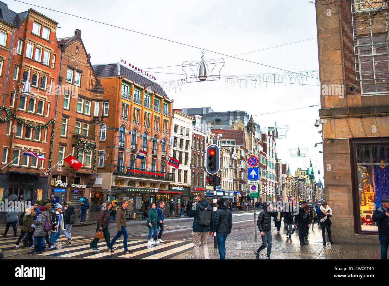 Der Amsterdamer Dome Square wird in Weihnachtslichtern lebendig, mit einer fröhlichen Straße voller Menschen, die die festliche Atmosphäre der Urlaubsmeere einfangen Stockfoto