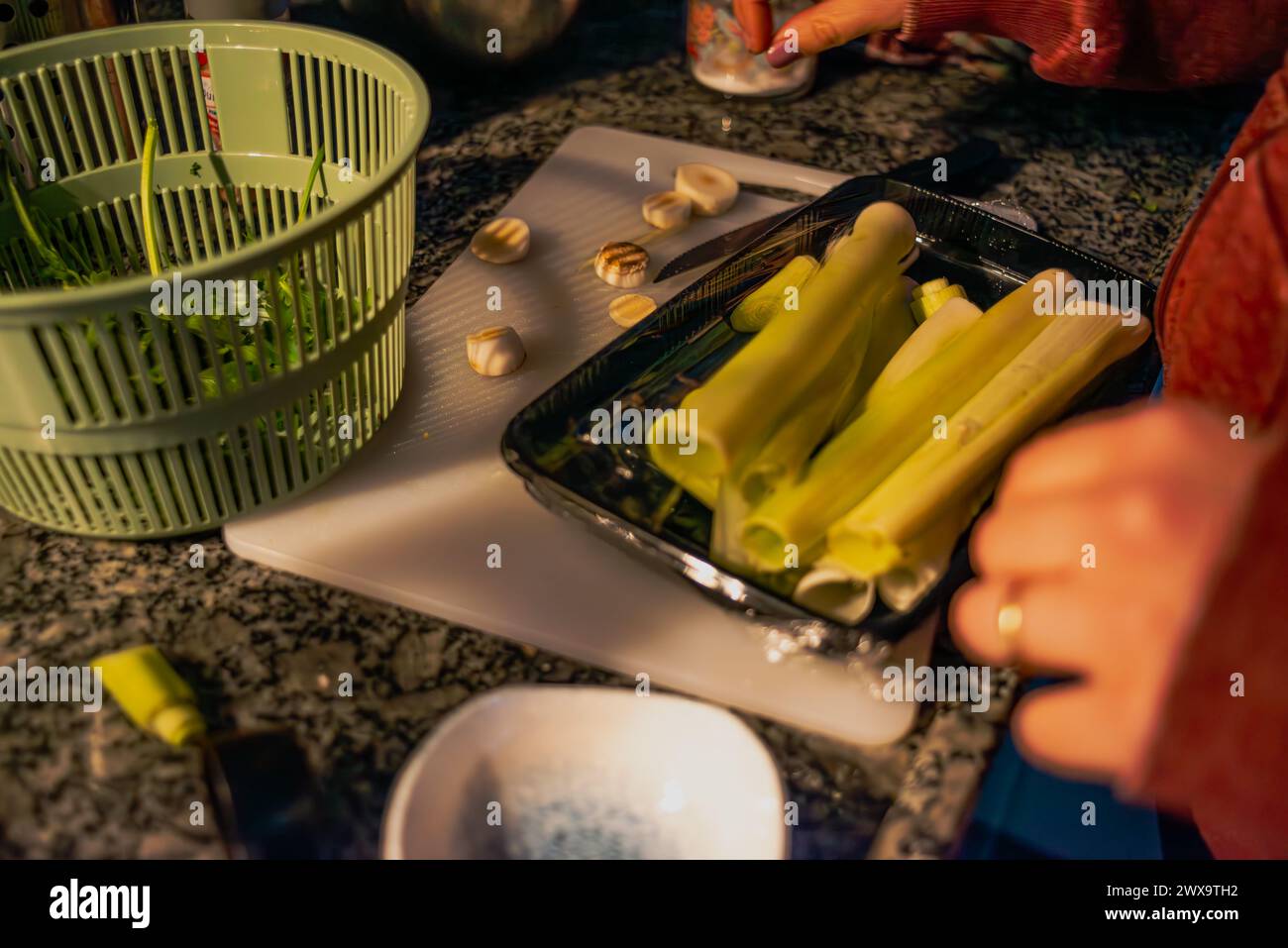 Eine kulinarische Symphonie entfaltet sich, während eine Frau mit einem Messer ein lebendiges Gemüse in der Küche schneidet und ein frisches und nahrhaftes Meisterwerk schafft Stockfoto