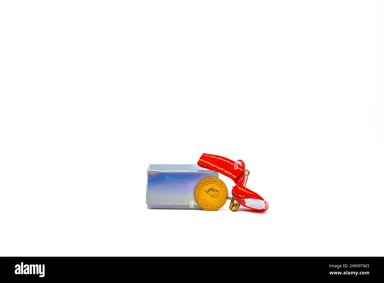 Eine Geschenkbox aus Gold im türkischen Viertel, die mit einem eleganten Band verziert ist, strahlt Opulenz und kulturelle Bedeutung auf einem unberührten weißen Hintergrund aus. Stockfoto