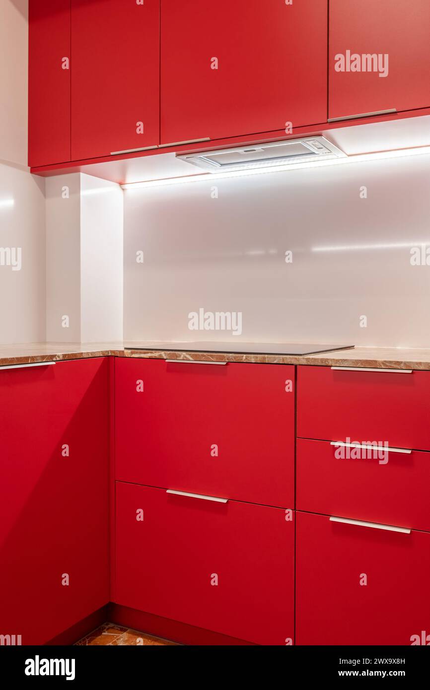 Minimalistische Küchenecke mit leuchtenden roten Schränken und weißen Wänden Stockfoto