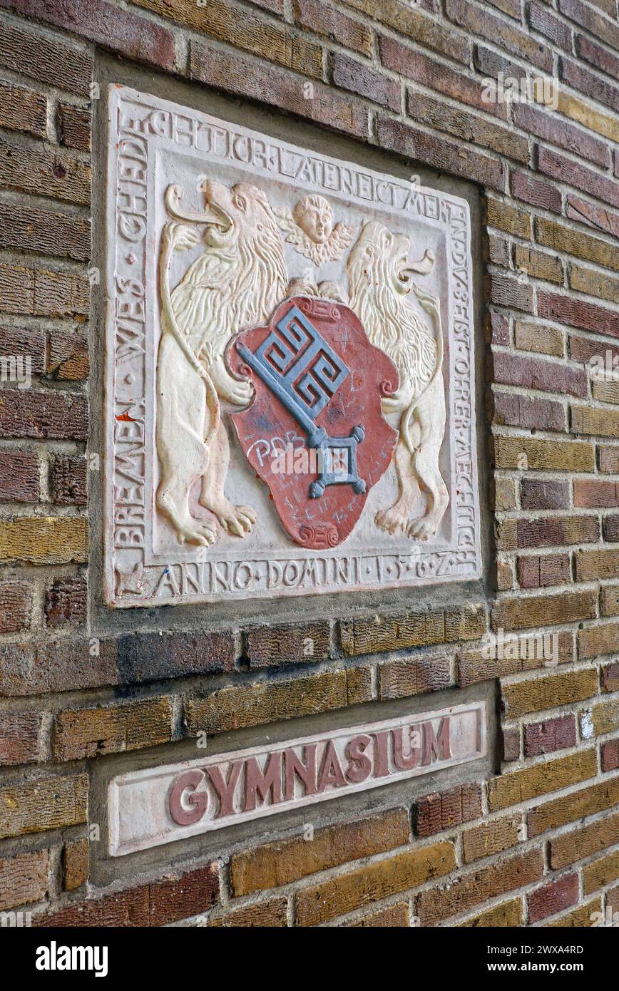 Ein sogenannter Wappenstein und ein Gymnasium-Schriftzug an einer Außenmauer der Oberschule am Leibnizplatz in Bremen, einem ehemaligen Gymnasium, das mittlerweile eine Gesamtschule ist. Der Wappenstein ist eine von mehreren Nachbildungen des Originals, das 1562 am damaligen Bremer Herdentor angebracht wurde. Die niederdeutsche Inschrift am Rand lautet: Bremen wes ghedechtich / late neict mer in / du beist ohrer mechtich / Anno Domini 1562 - Wörtliche Übersetzung laut Stadthistoriker Peter Strotmann: Bremen sei bedächtig, lass nicht mehr ein, du seiest ihrer mächtig. Anno Domini 1562. - Sinngemä Stockfoto