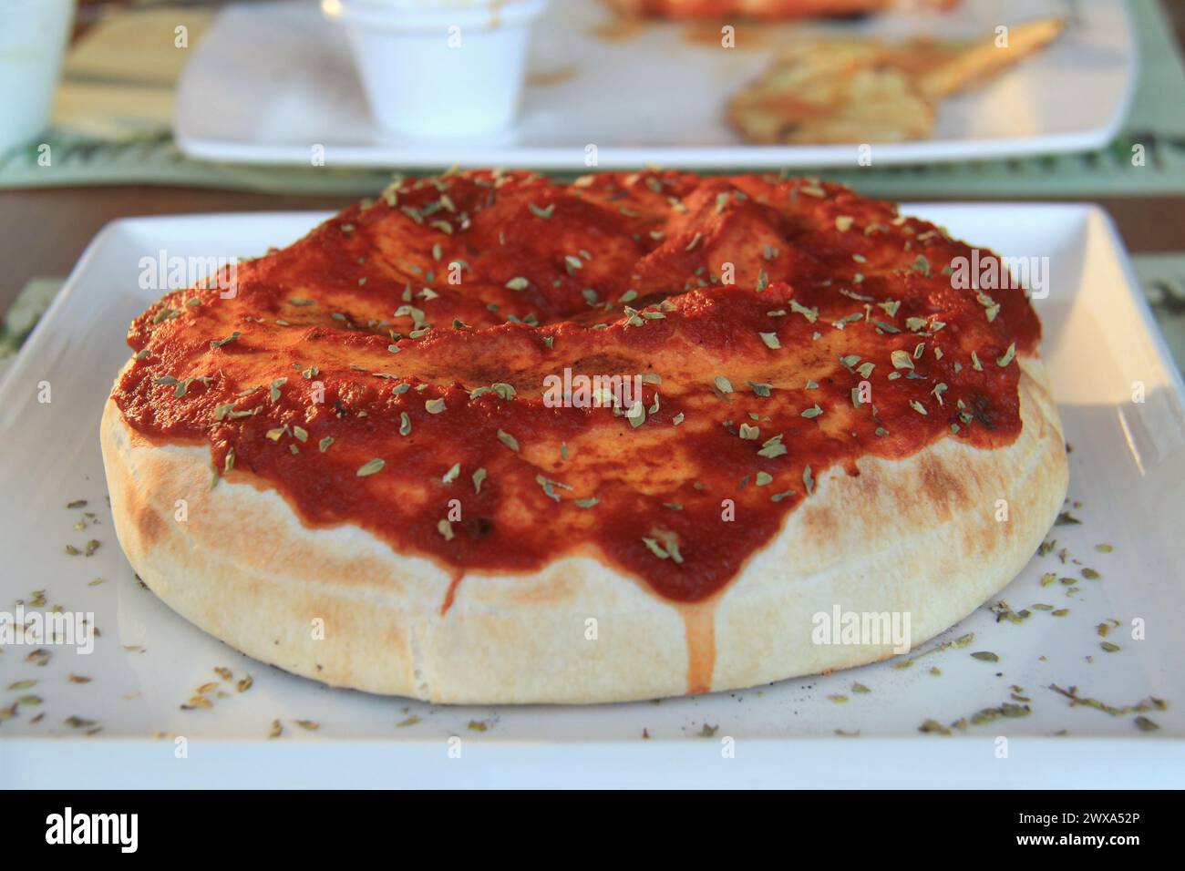 Eine Calzone mit Tomatensauce und Kräutern auf einem Teller. Stockfoto