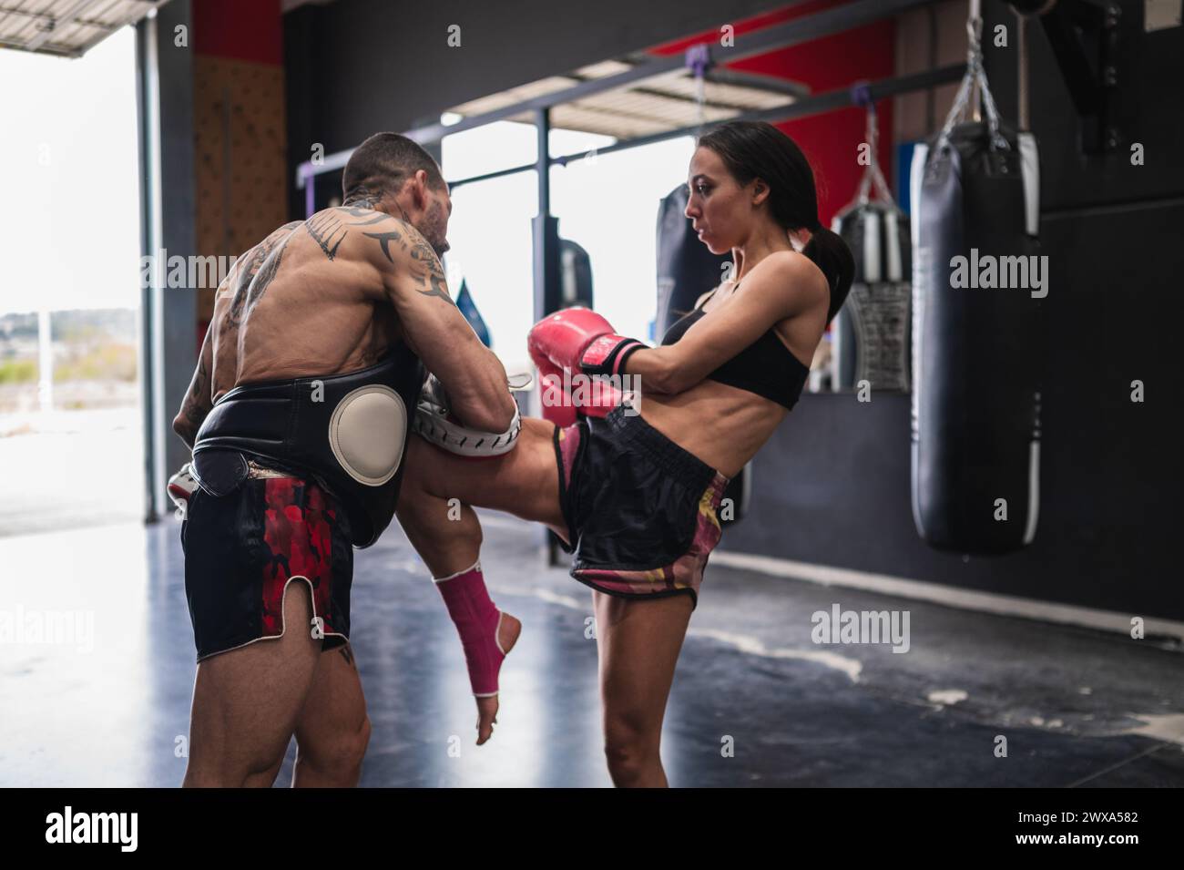 Kampfkünstlerin-Sparring mit Personal Trainer im Fitnessstudio Stockfoto