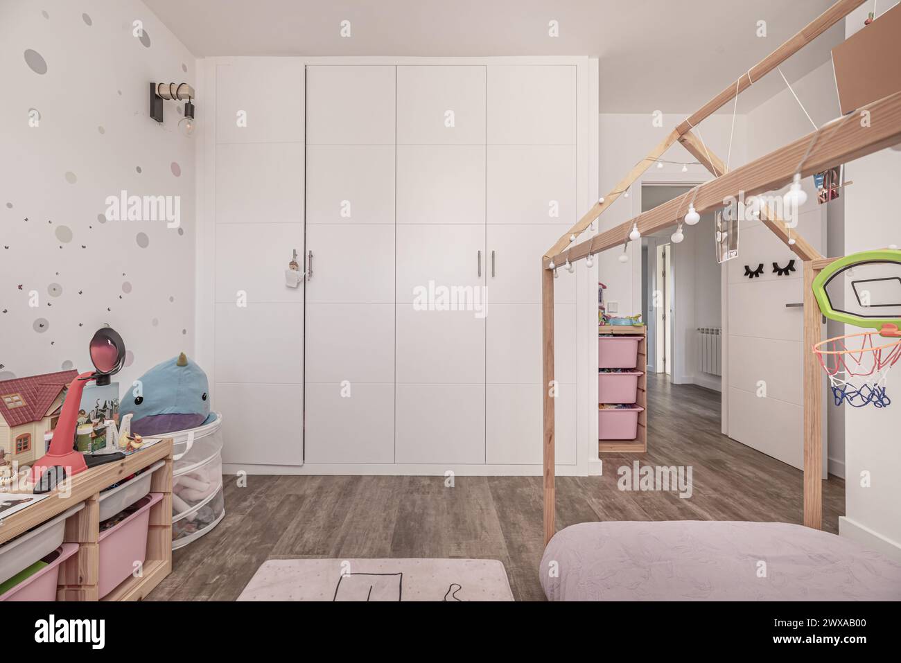 Kinderzimmer mit großem Einbauschrank mit weißen Türen und Bett mit unbehandelter Holzstruktur Stockfoto