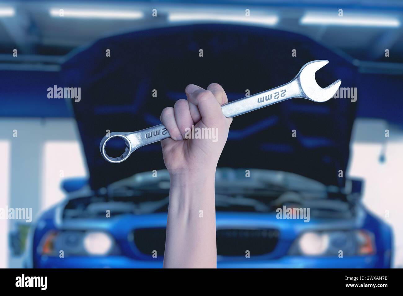 Schlüssel in der Hand vor einem blauen Auto mit offenem Motorraum. Bereit für Service und Wartung. Professionelles Automobilkonzept Stockfoto