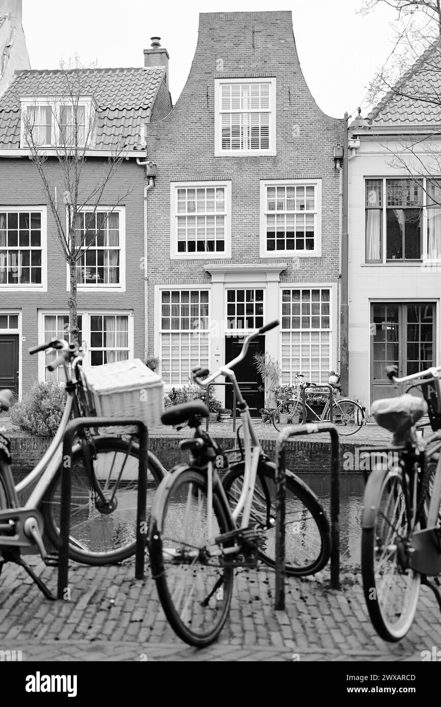 Malerische Niederlande in Schwarz-weiß. Fahrräder parkten entlang eines Kanals auf wunderschönen alten Gebäuden Hintergrund. Stockfoto