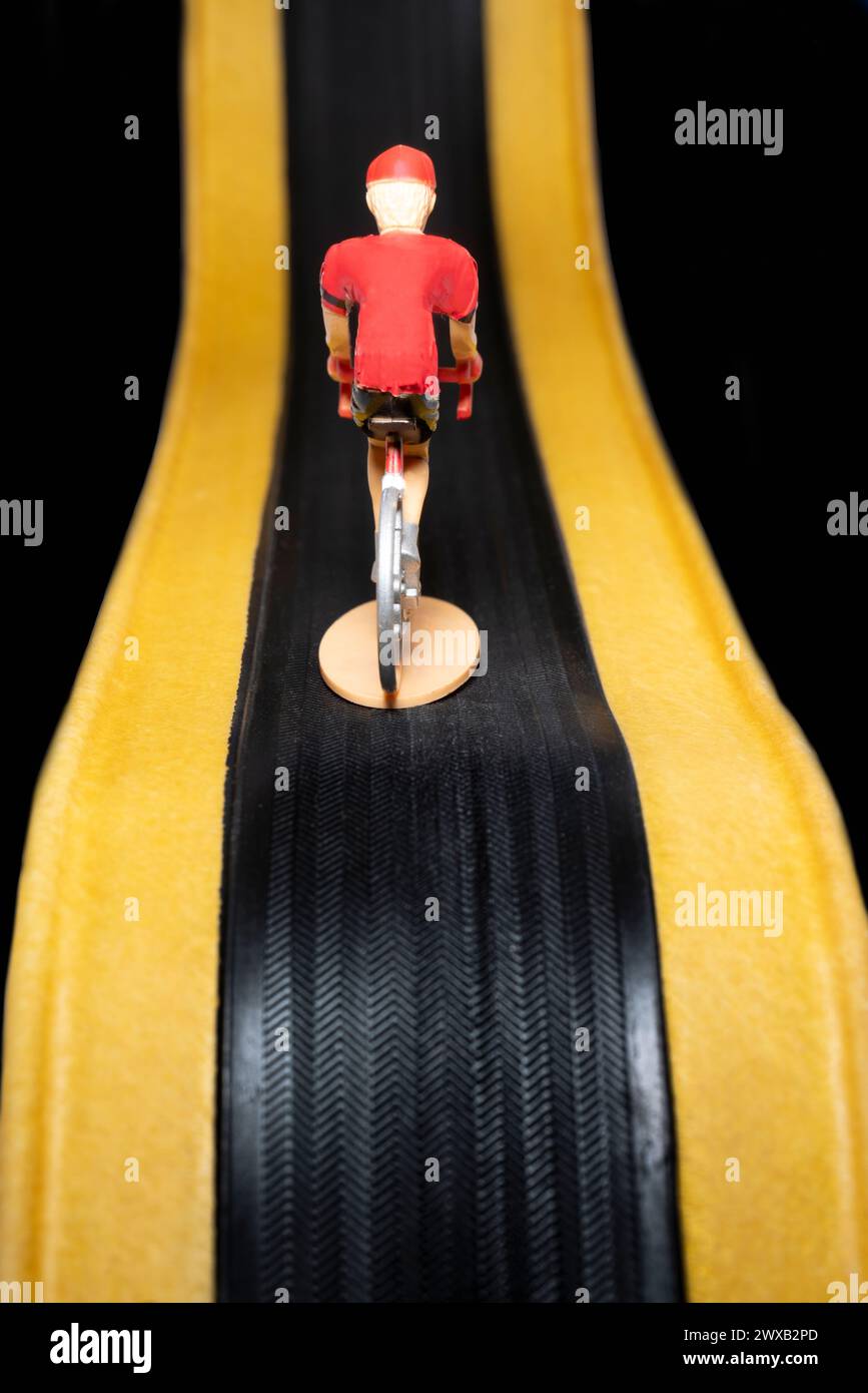 Miniaturspielzeug-Rennradfahrer auf Reifenprofil Stockfoto