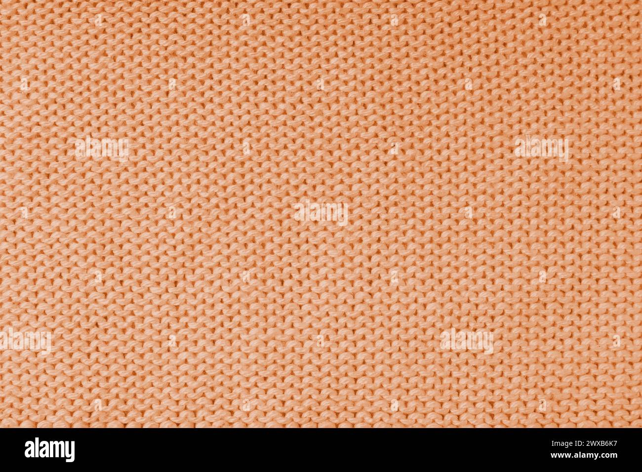Nahaufnahme des Hintergrunds des gestrickten Wollgewebes aus Viskosegarn, orangefarbene Wollstricktextur. Pullover mit gestricktem Jersey-Hintergrund. Fabr Stockfoto