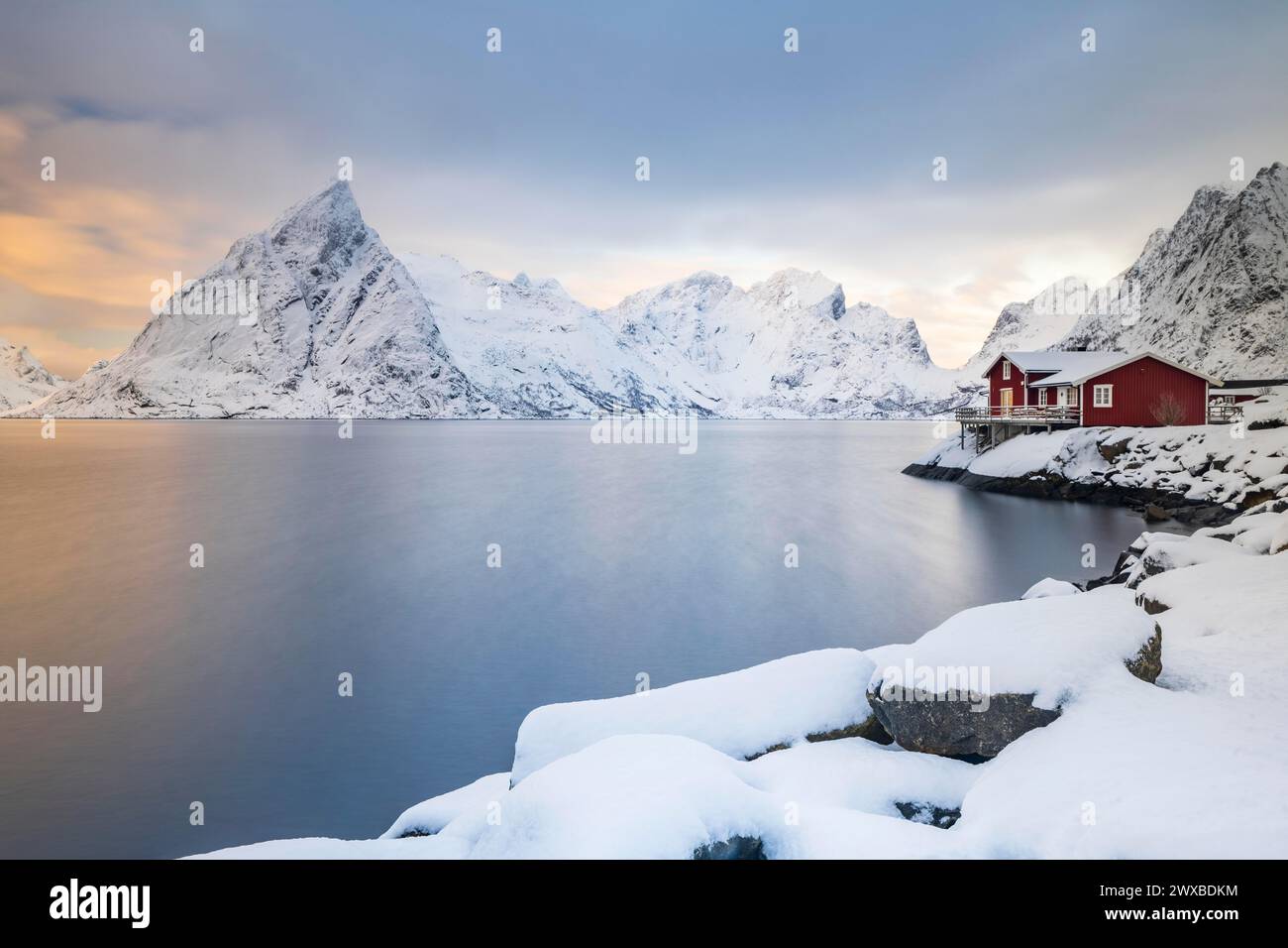 Rote Hütten auf der Insel Sakrisoy, schneebedeckte Berge im Hintergrund, Sakrisoy, reine, Lofoten, Norwegen Stockfoto