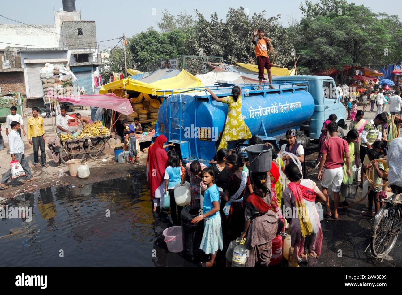 Menschen versammeln sich um einen Wassertanker, um sie in einer städtischen Umgebung zu versorgen, Rajasthan, Nordindien, Indien Stockfoto