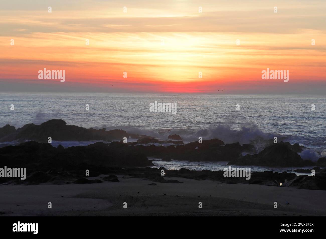 Der Sonnenuntergang erzeugt eine ruhige Atmosphäre über dem Meer mit Felsen und einem lila Himmel in der Nähe von Mindelo, Porto, Nordportugal, Portugal Stockfoto