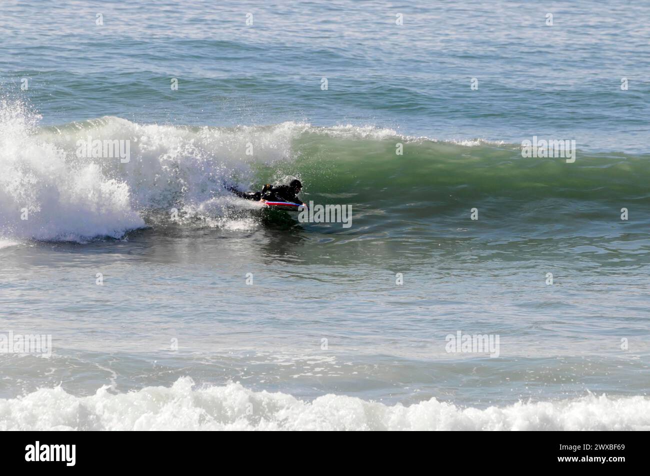 Ein Surfer in schwarzer Kleidung reitet im Norden Portugals in der Nähe von Mindelo, Portugal Stockfoto