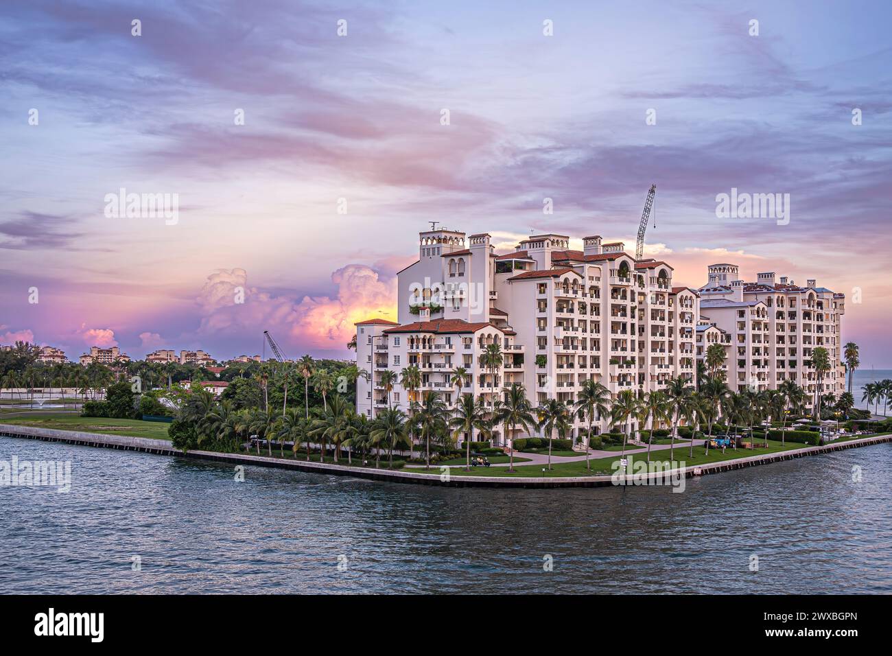 Miami, Florida, USA - 29. Juli 2023: Pilz-orange Sonnenuntergang Wolke versteckt hinter Luxuswohnungen entlang Fisher Island Ecke unter Abendhimmel. GREE Stockfoto