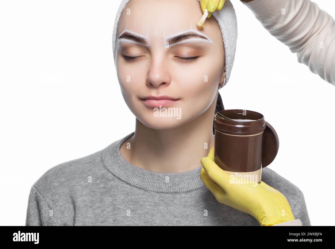Die Make-up-Künstlerin zupft sich die Augenbrauen, bevor sie im Schönheitssalon dauerhaft schminkt. Stockfoto