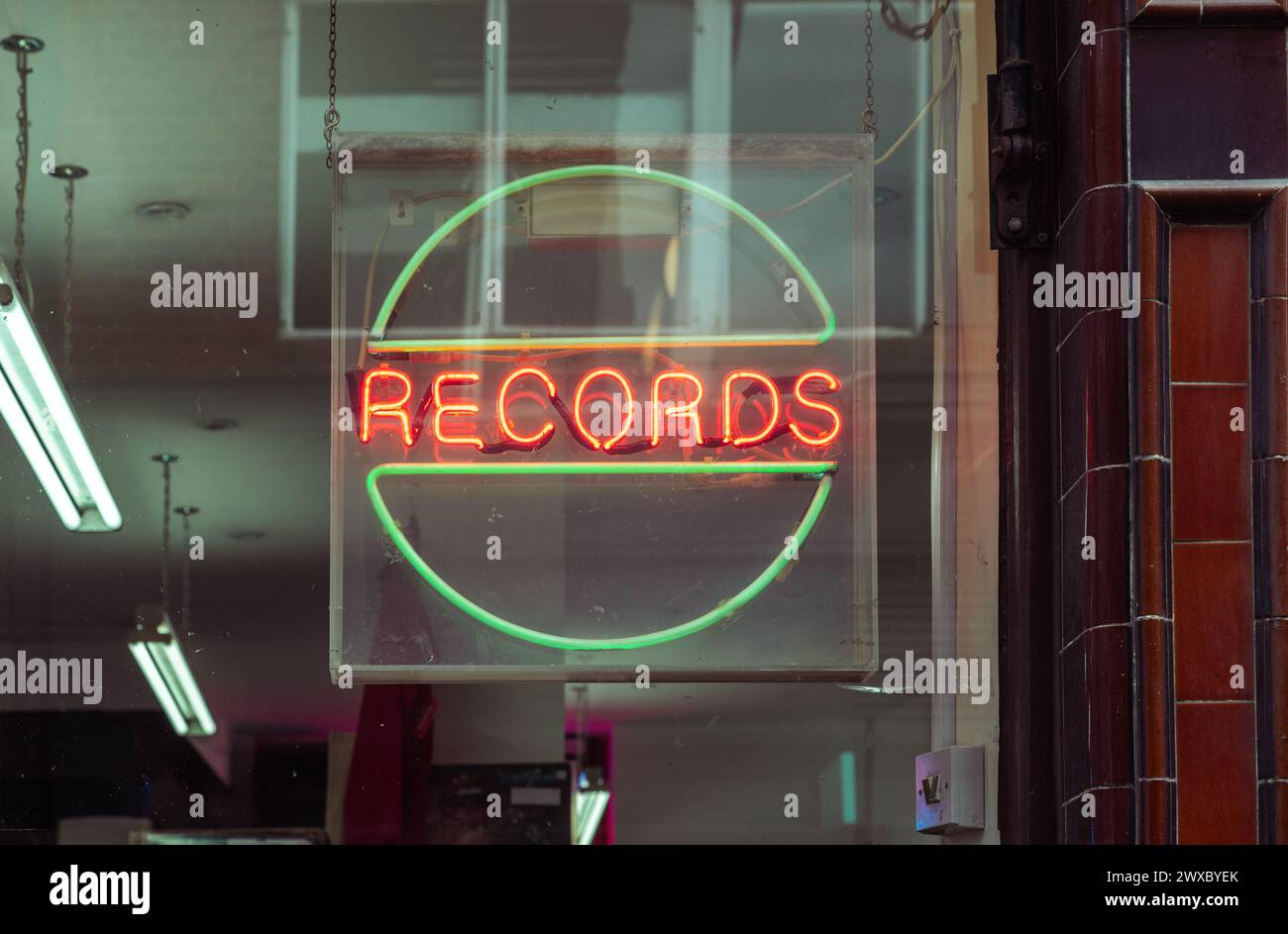 Ein Neonzeichen, das Datensätze im Fenster eines Plattengeschäfts anzeigt. Tag des Plattengeschäfts, Verkauf von Schallplatten, Musikindustrie oder Konzept für das Sammeln von Schallplatten. Stockfoto