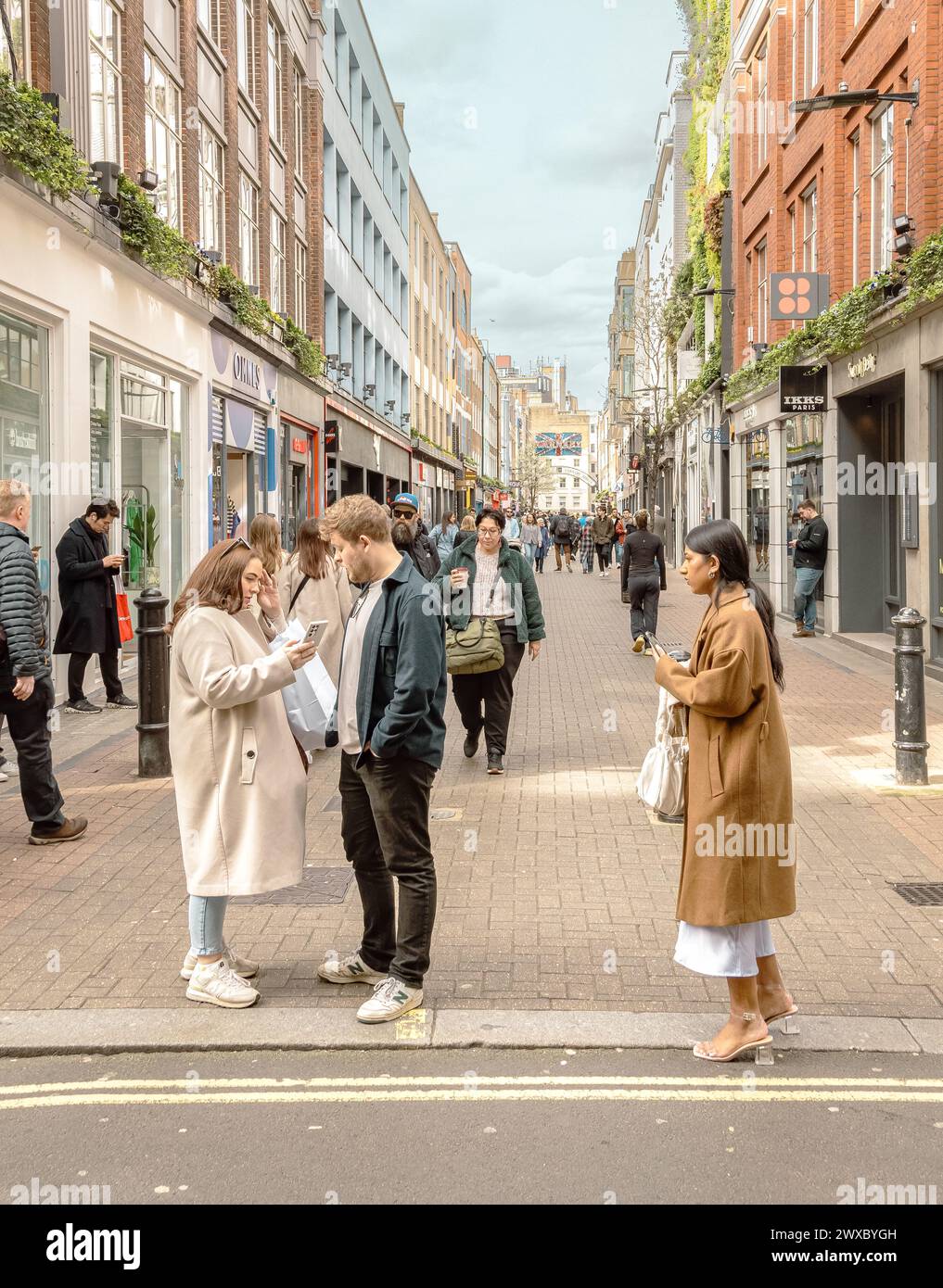 Shopper und Touristen in der Carnaby Street, dem legendären Zentrum, das Mode, Kultur und pulsierendes Straßenleben im Herzen von Soho, London, verbindet. Stockfoto