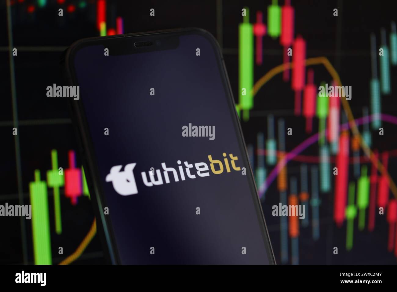 KIEW, UKRAINE - 15. MÄRZ 2024 Whitebit-Logo auf dem iPhone-Display und Kryptowährungswertdiagrammen. Portal für den Austausch von Kryptowährungen Stockfoto