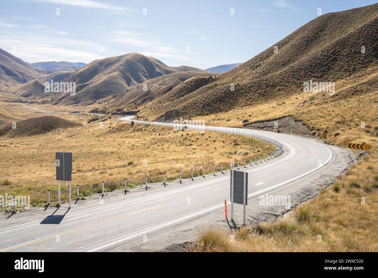 Kurvige Straße, die durch einen hohen Bergpass mit herbstlichen Farben im Lindis Pass, Neuseeland, führt. Stockfoto