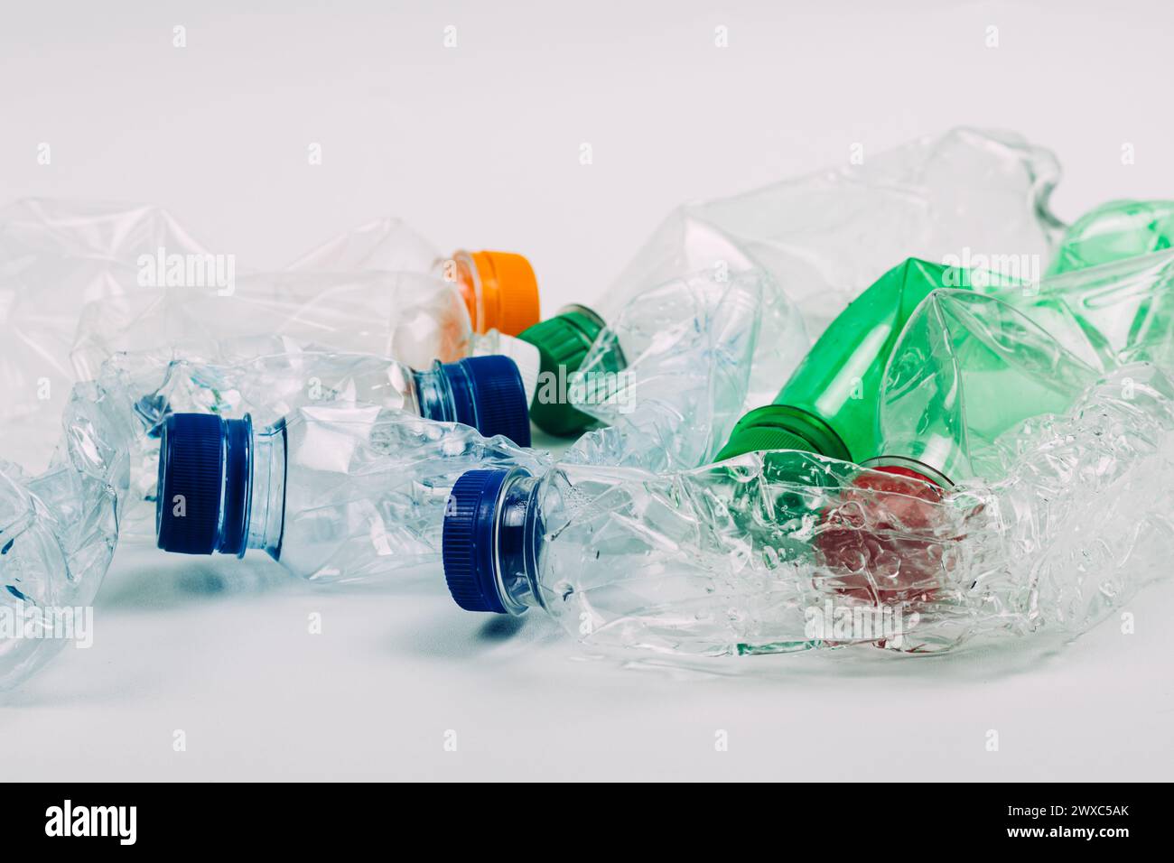 Stapel zerdrückter gebrauchter Kunststoffflaschen auf weißem Hintergrund. Stockfoto