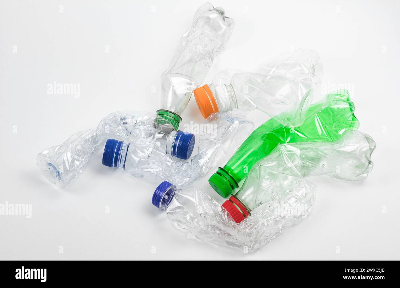 Stapel zerdrückter gebrauchter Kunststoffflaschen auf weißem Hintergrund. Stockfoto