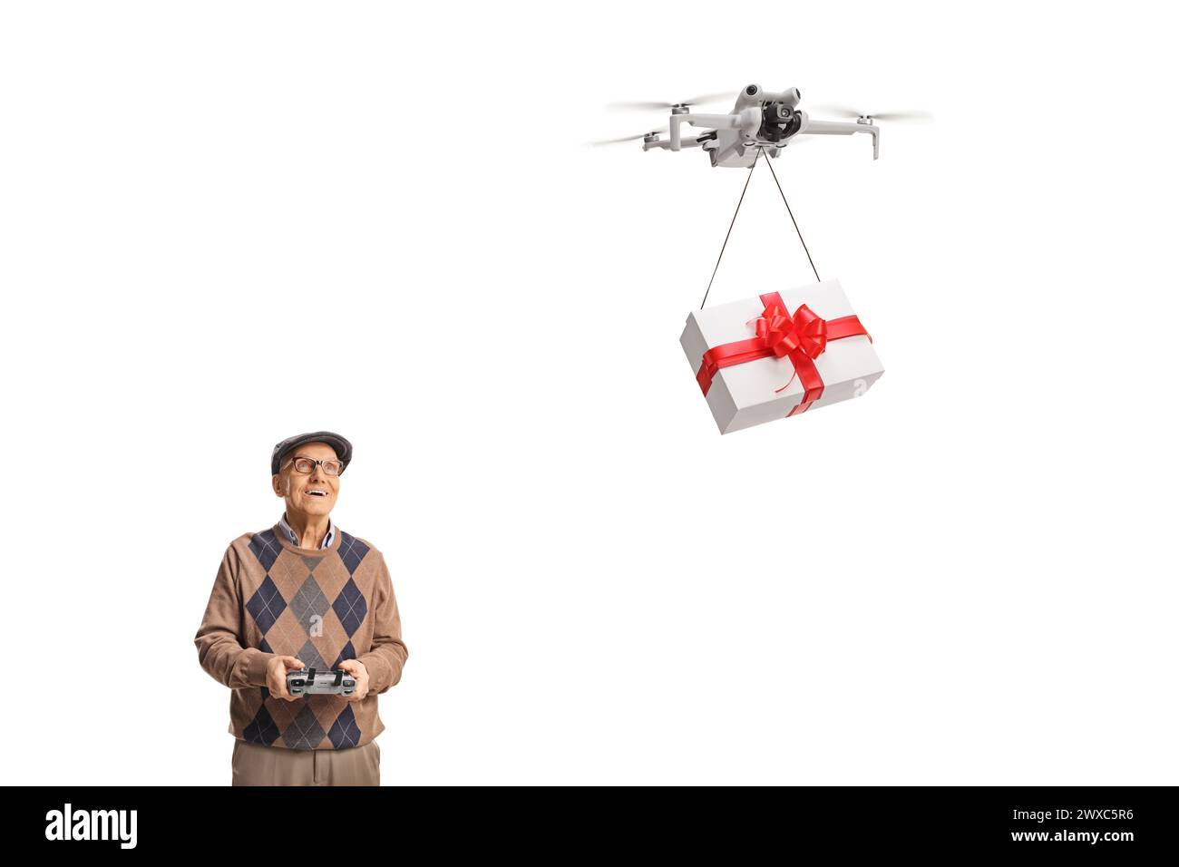 Ein älterer Mann, der eine Drohne mit einer Fernbedienung fliegt und ein Geschenk isoliert auf weißem Hintergrund abgibt Stockfoto