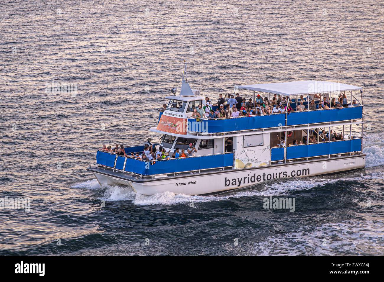 Miami, Florida, USA - 29. Juli 2023: Bayridetours Island Windboot Nahaufnahme des Sonnenuntergangs, das Hafenwasser reflektiert. Viele Leute an Deck Stockfoto