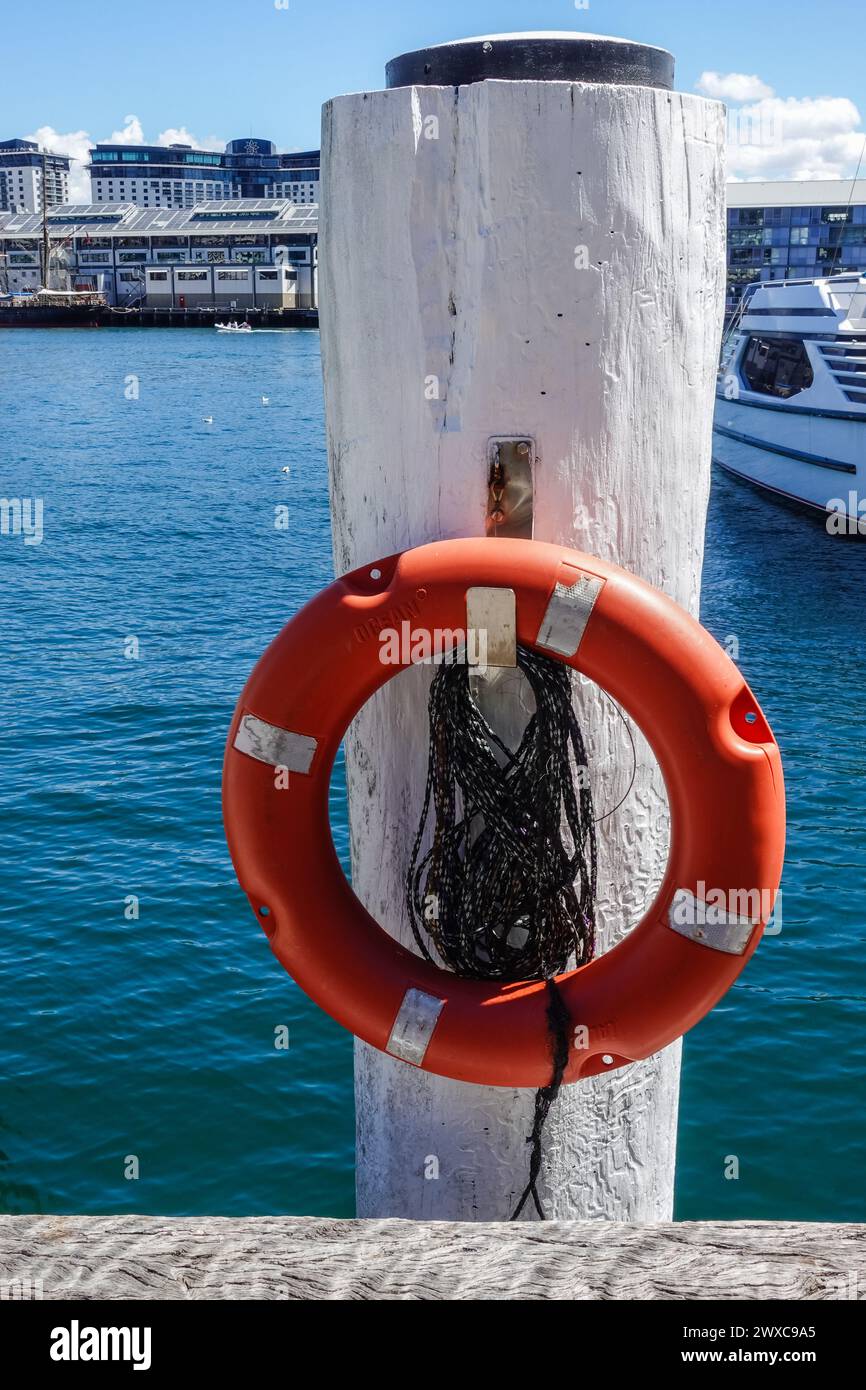 Ein orangener Rettungsring, montiert auf einem weißen Holzpfosten an einem Dock in Sydney, Australien Stockfoto