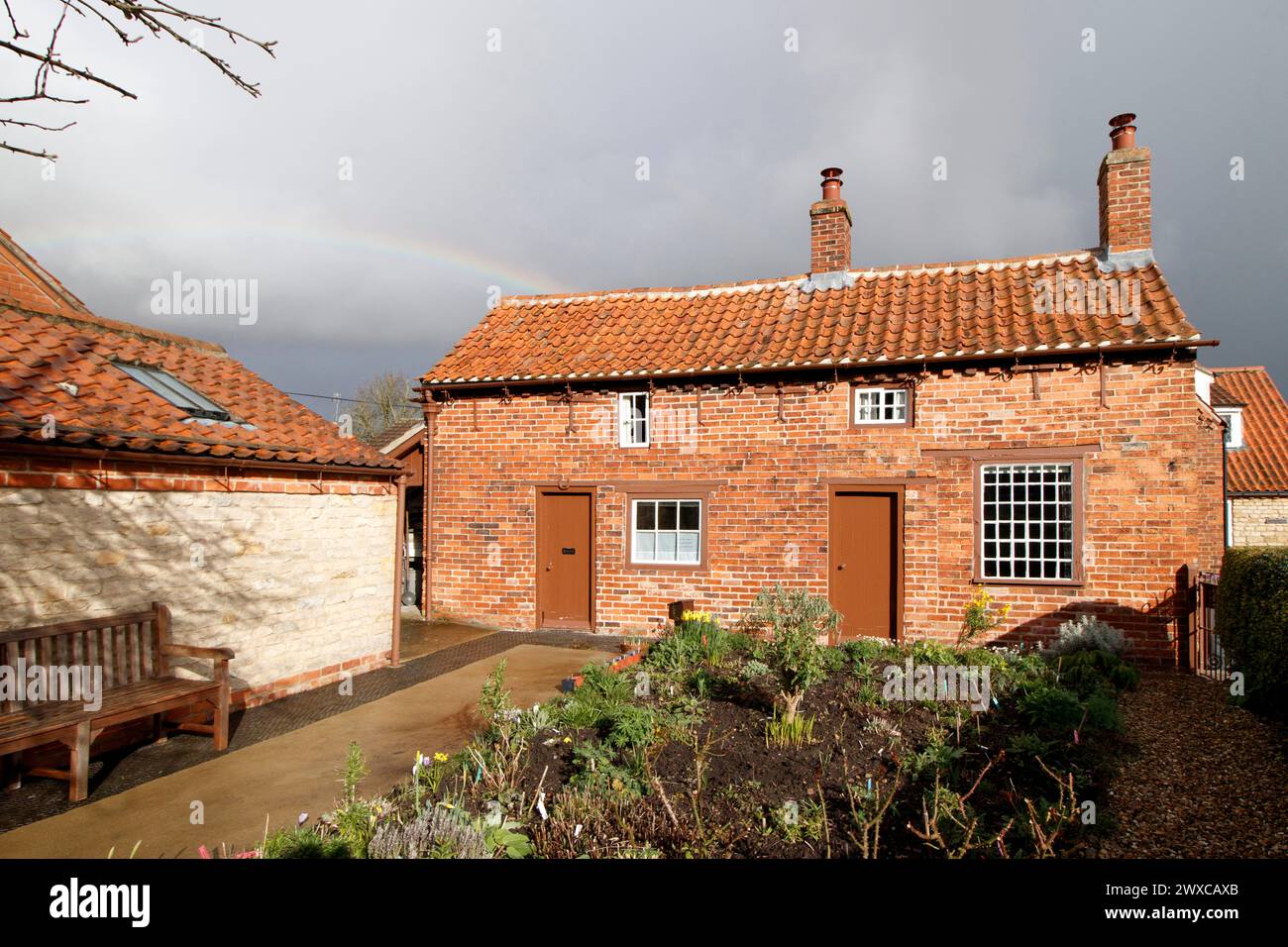 Hinter dem Cottage, in dem einst Mrs. Smith in Navenby, Lincolnshire, lebte, erscheint ein Regenbogen. Das von der örtlichen Gemeinde gerettete, bescheidene Haus von Mrs. Smith wurde 1999 erstmals als Museum eröffnet. Durch die Zusammenarbeit von lokalen Freiwilligen und dem District Council zieht die Stätte Besucher und Lob von weit und breit an. Stockfoto