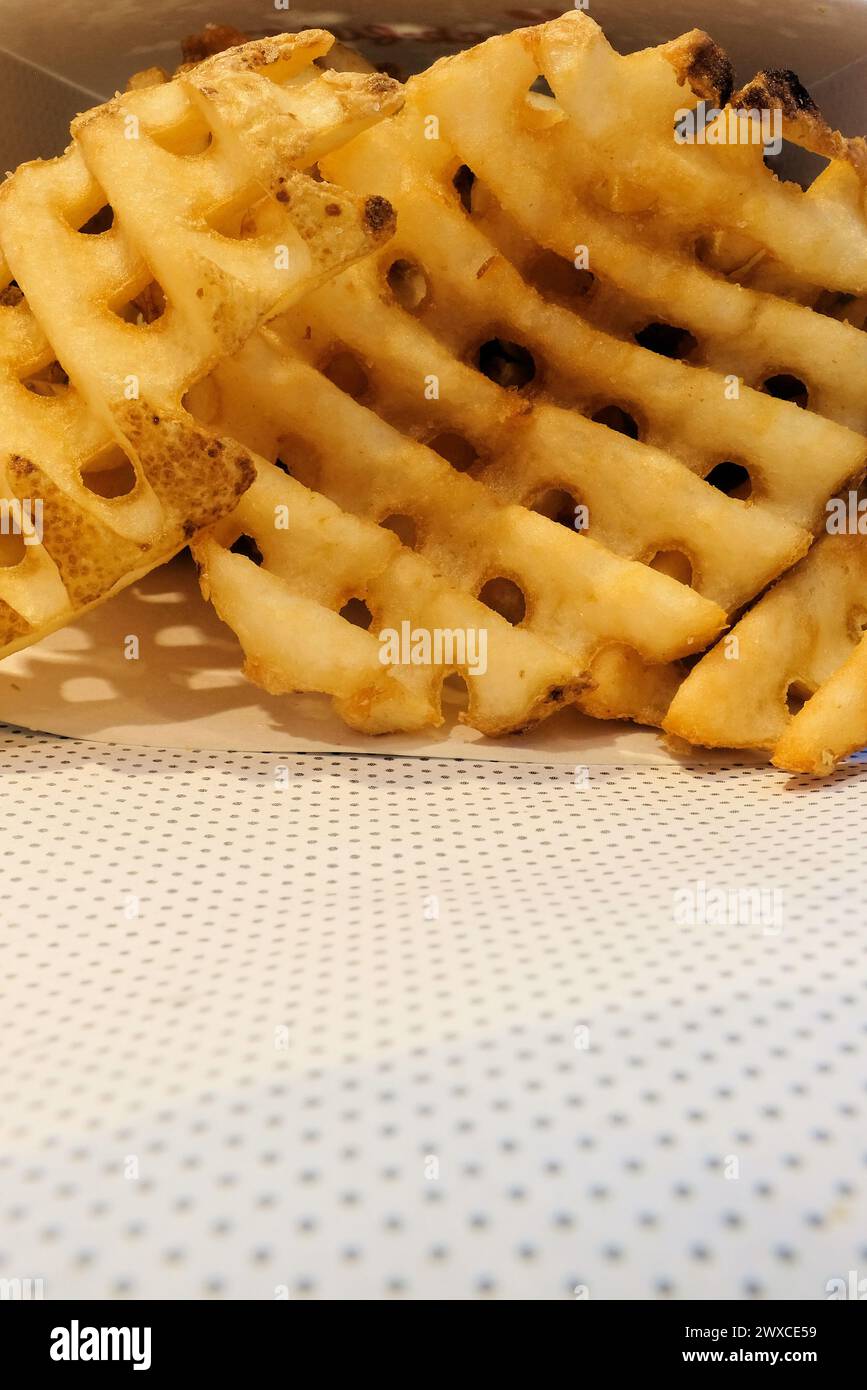 Nahaufnahme von knusprigen goldbraunen Waffelfritten, Crisscut- oder Criss-Crosscut-Pommes; eine Variante von Pommes Frites, die in Fast-Food-Restaurants serviert werden. Stockfoto
