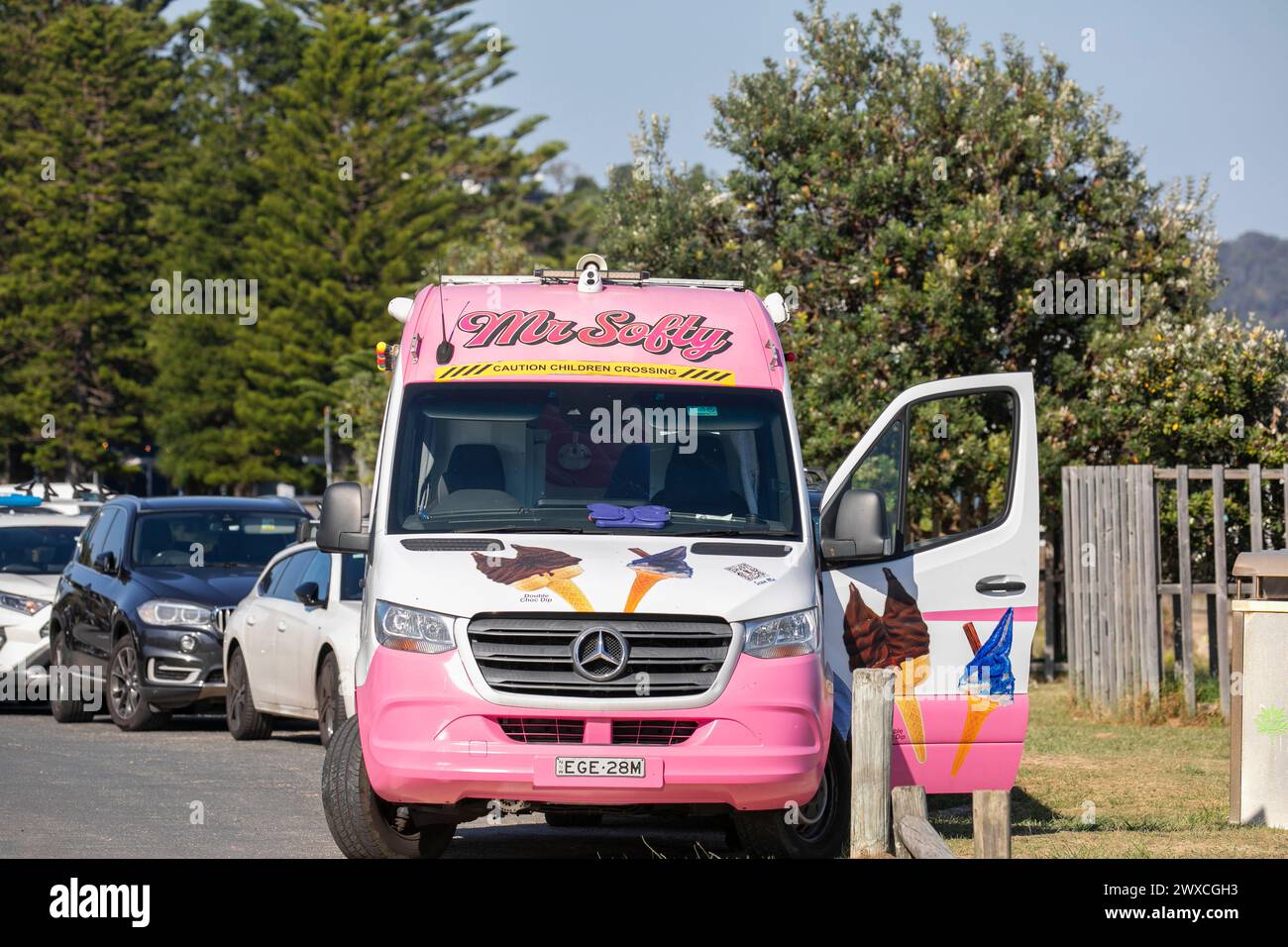Mr Softy Eisverkäufer, der vom traditionellen Eiswagen in Pink, Palm Beach, Sydney, Australien während des heißen osterwochenendes 2024 fährt Stockfoto