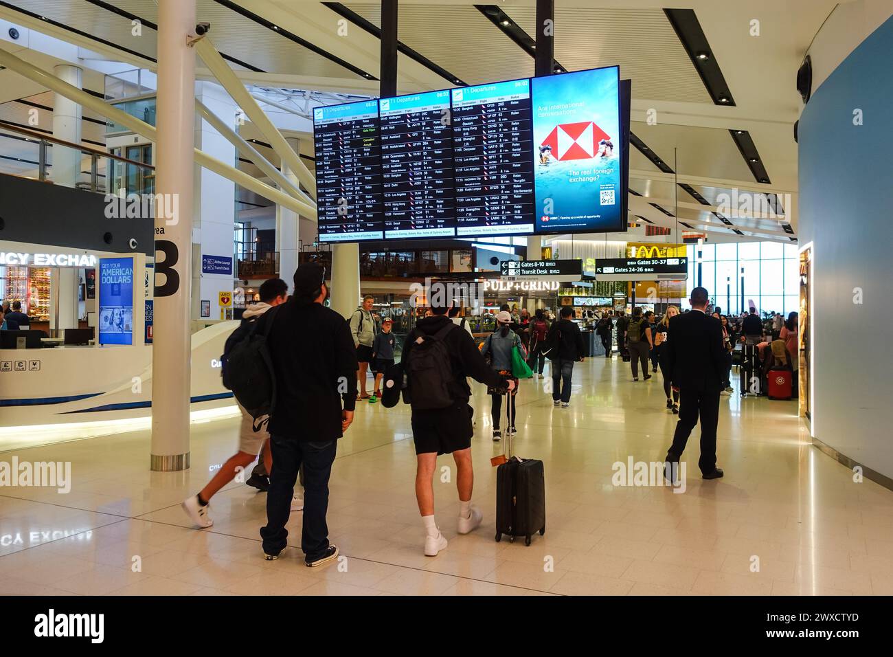 Leute, die die Flugstatthaltertafel im Flughafen sydney überprüfen Stockfoto