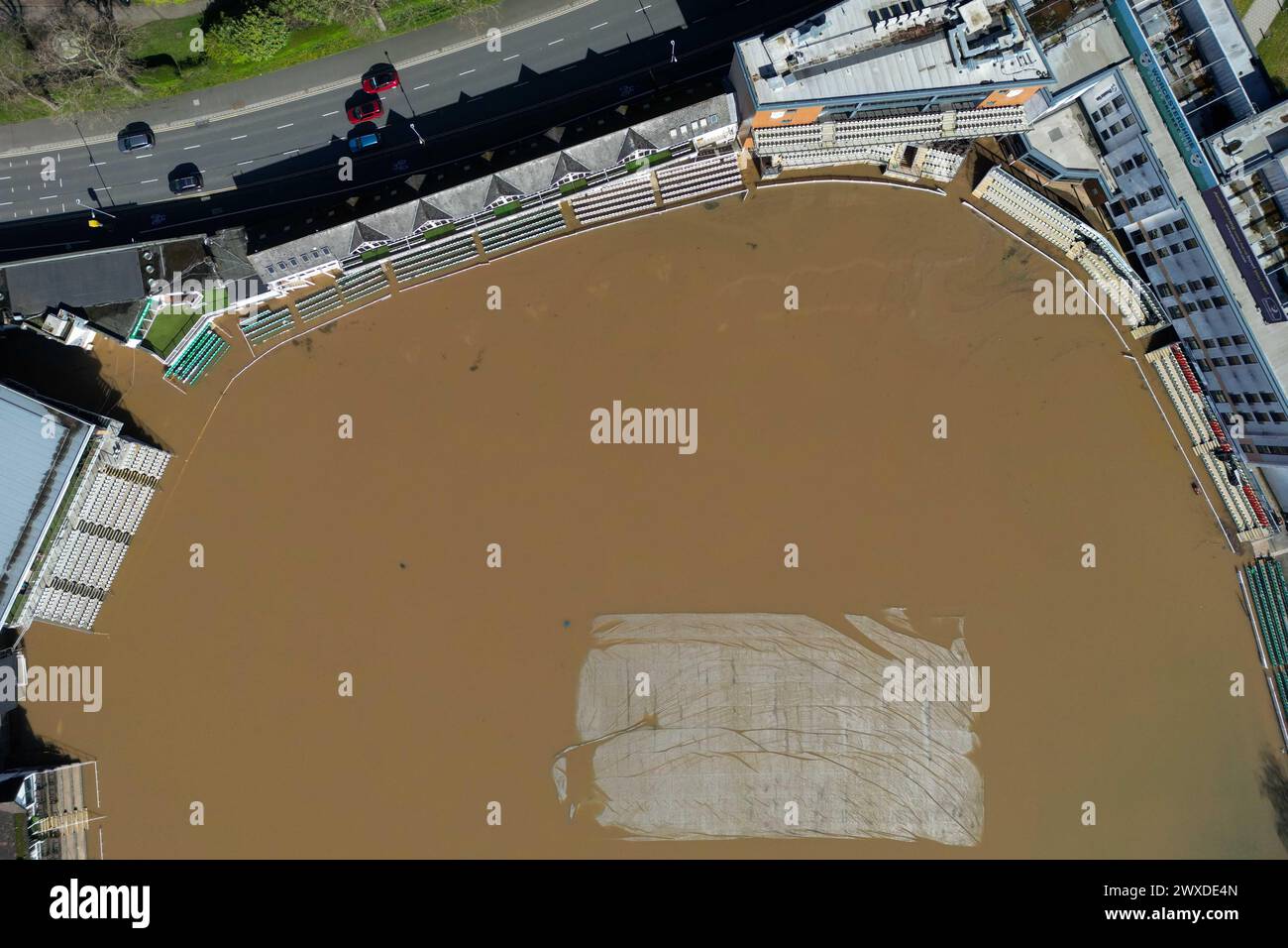 Eine Luftaufnahme zeigt Fahrzeuge, die an einem überfluteten New Road Cricket Club, dem Heimstadion von Worcestershire CCC, in Worcester vorbeifahren. Bilddatum: Samstag, 30. März 2024. Stockfoto