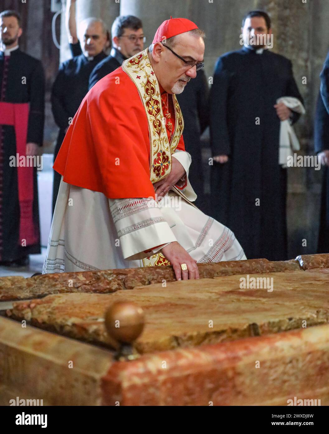 Jerusalem, Israel. 30. März 2024. Der katholische Lichtsamstag in der Grabeskirche. Pierbattista Pizzaballa, Jerusalems Erzbischof tritt in die Kirche ein und hockt sich beim Stein der Sühne. Stockfoto