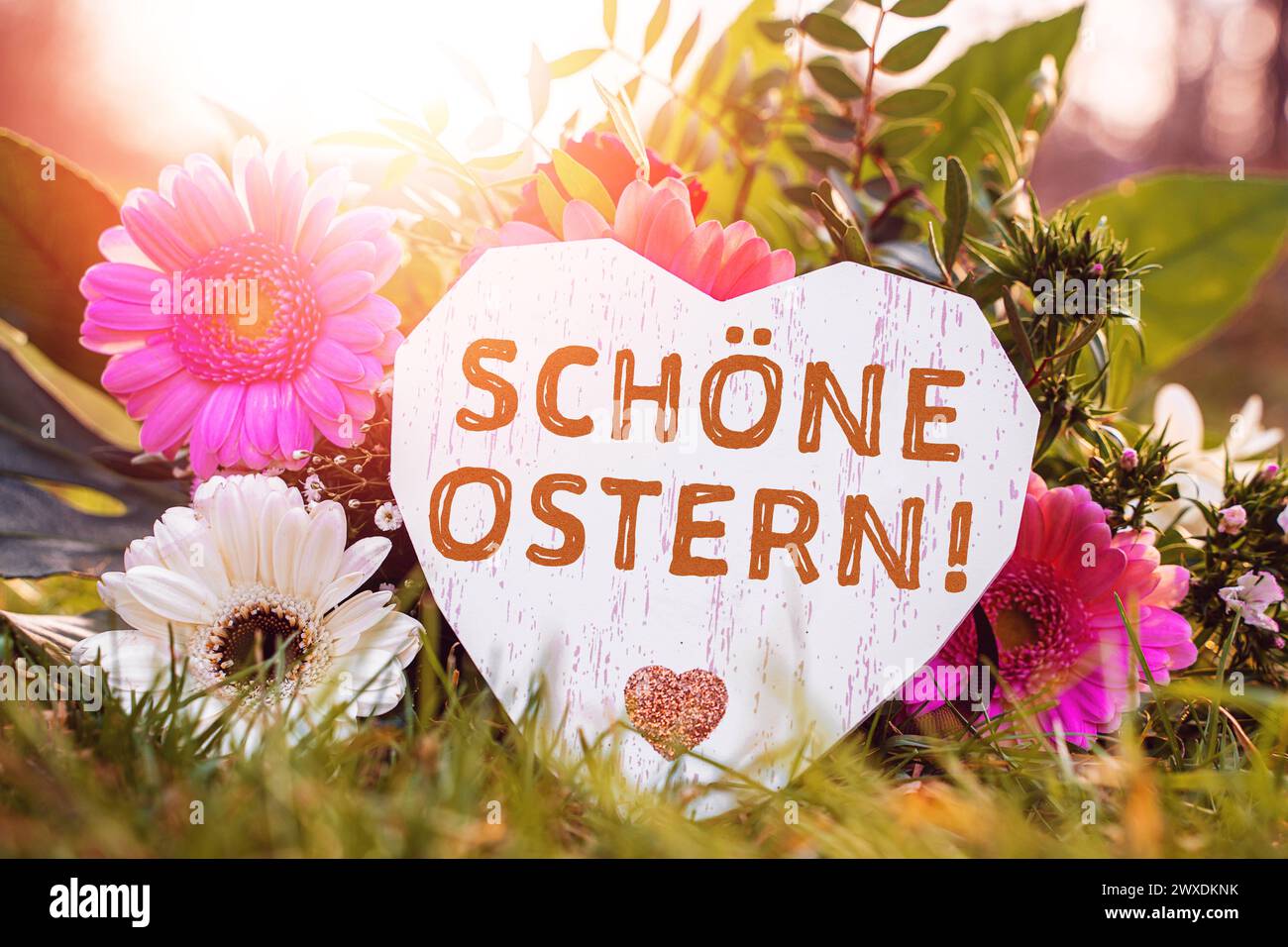 30. März 2024: Ostergrüße: Frohe Ostern auf einem hölzernen Herzen vor einem Blumenstrauß. FOTOMONTAGE *** Ostergrüße: Schöne Ostern auf einem Herz aus Holz vor einem Blumenstrauß. FOTOMONTAGE Stockfoto