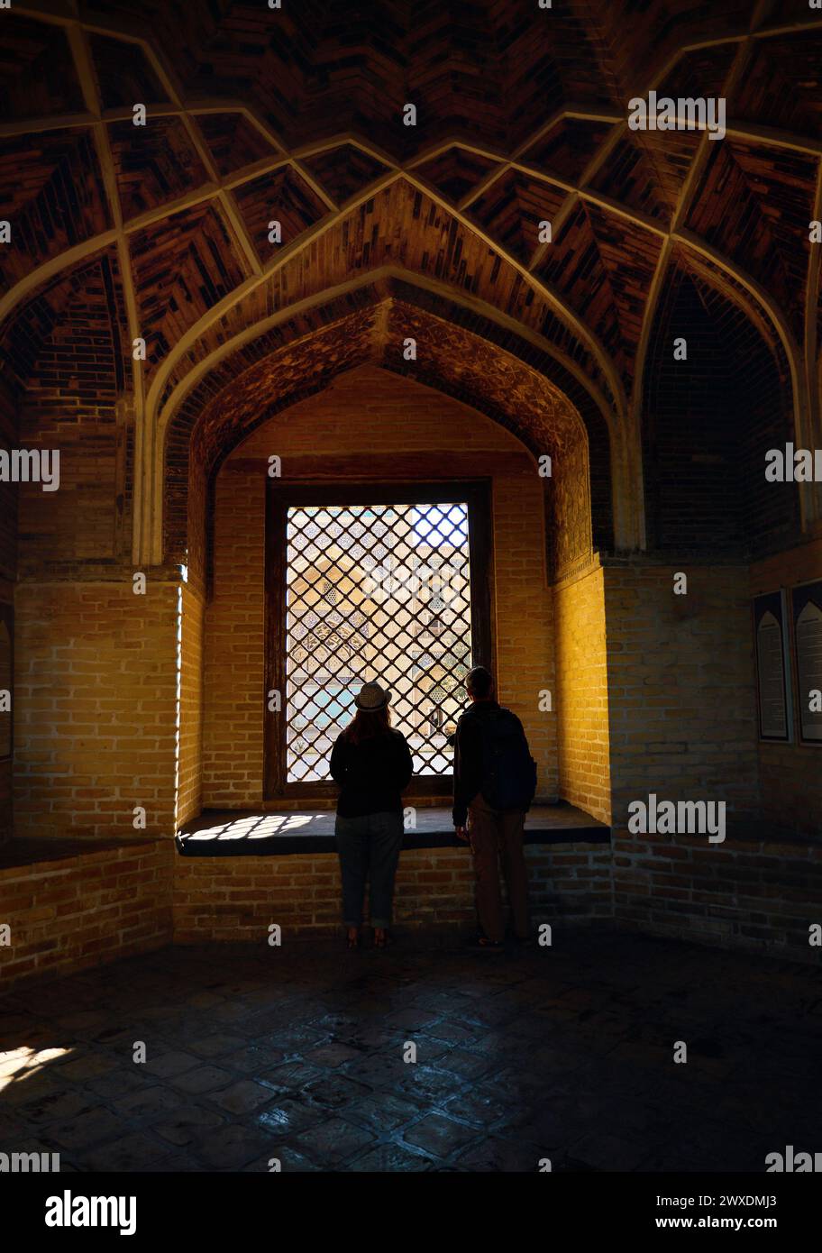 Wunderschöner Blick auf das Wahrzeichen von Madrasah und die Touristensilhouette der Menschen vor dem Fenster zum Innenhof in der Altstadt von Bokhara, Usbekistan Stockfoto