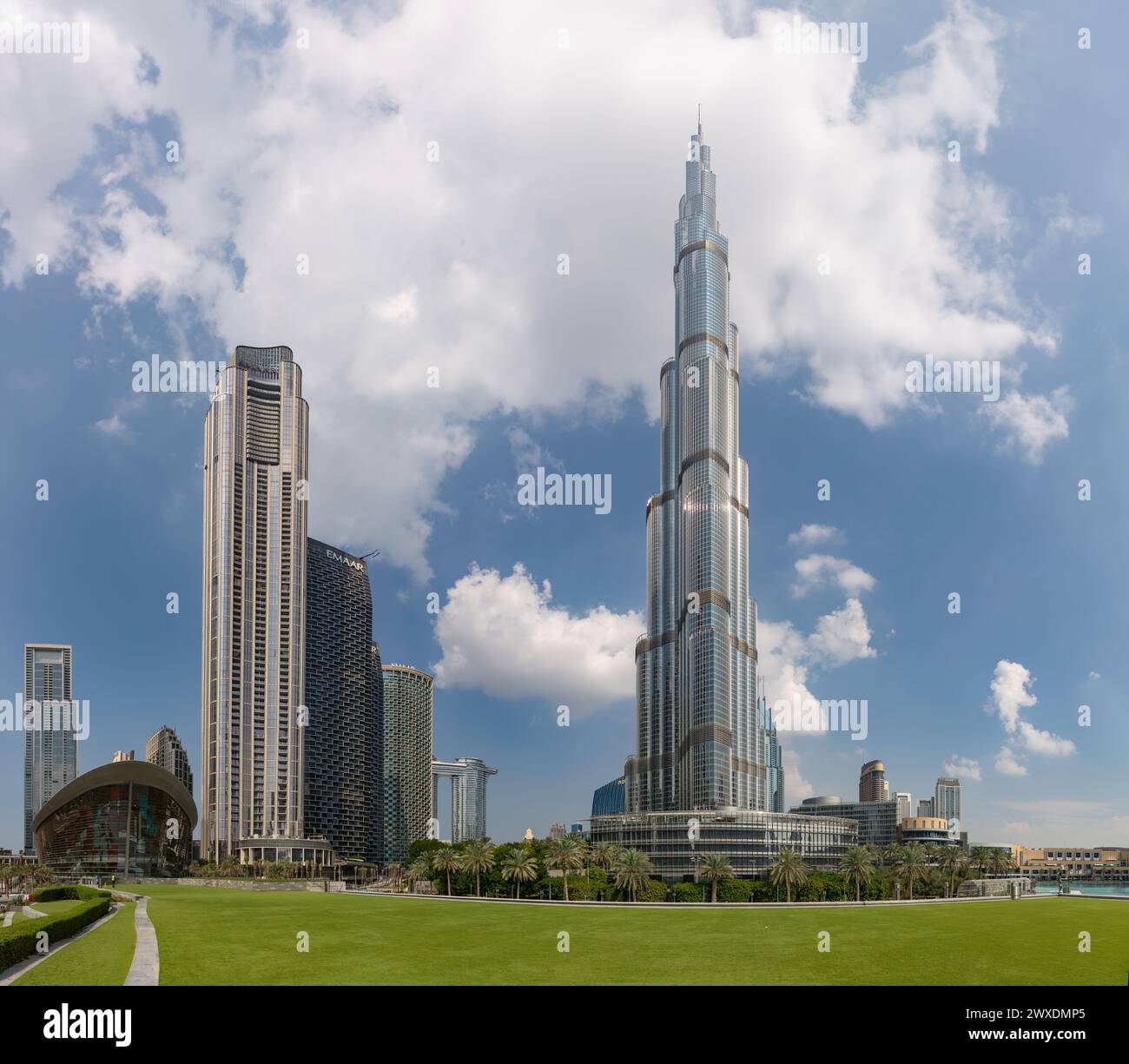 Ein Bild des Burj Khalifa, der die nahe gelegenen Gebäude in der Innenstadt von Dubai und das grüne Gras des Burj Khalifa Parks überragt. Stockfoto