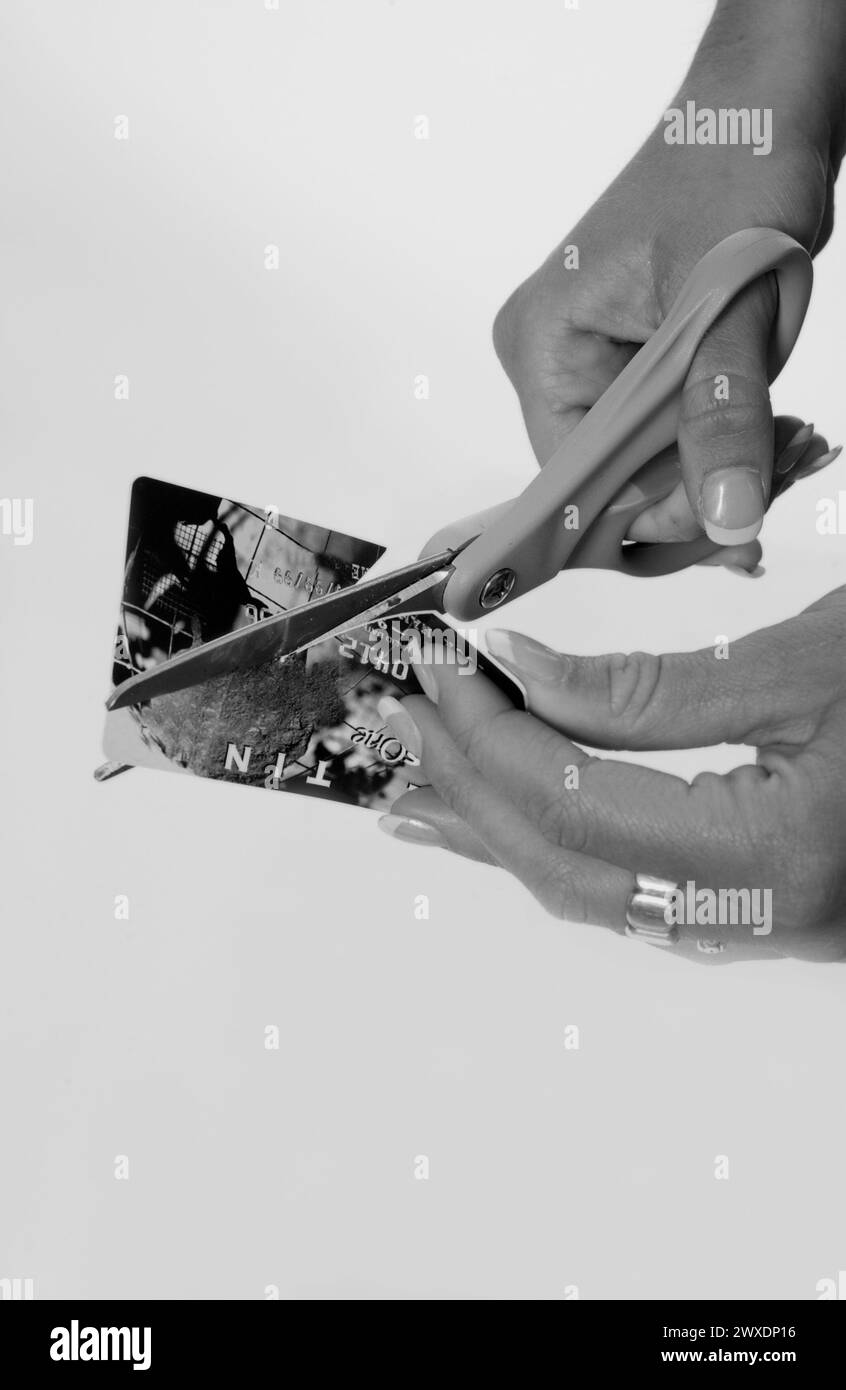 Das Mädchen schneidet Kreditkarten mit einer Schere Stockfoto