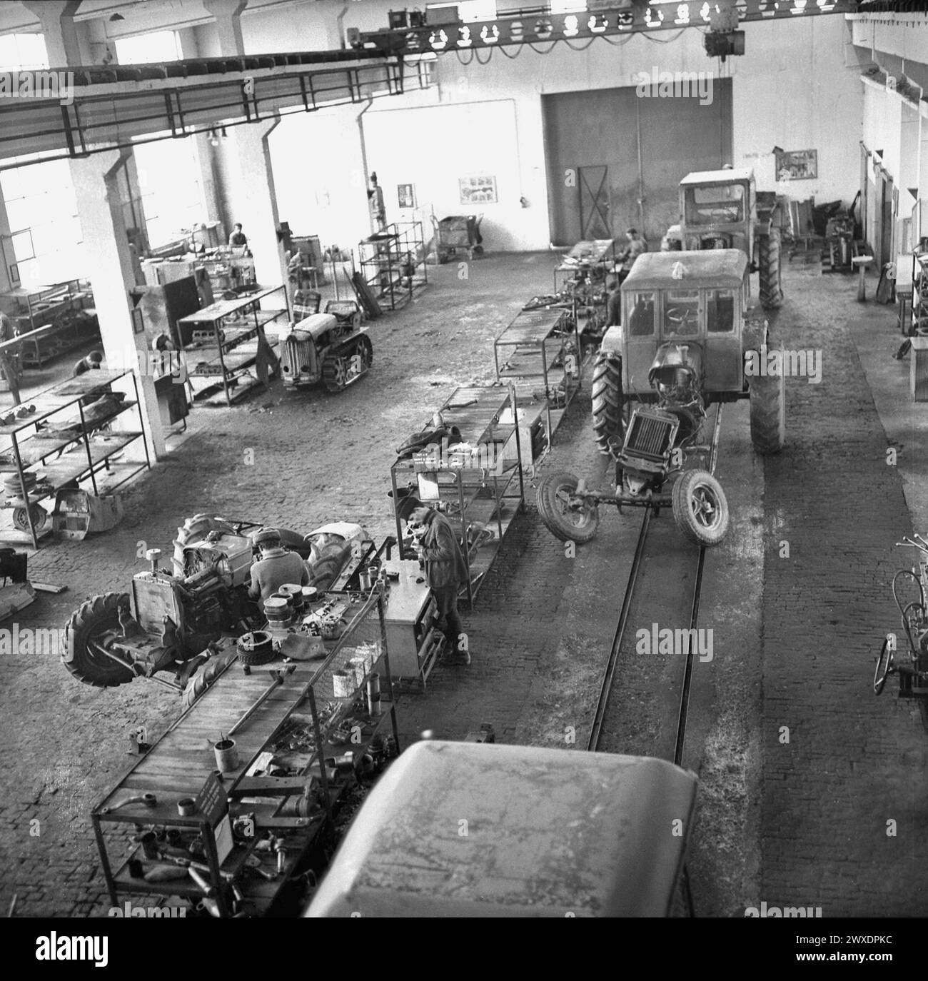 Die Sozialistische Republik Rumänien in den 1970er Jahren Arbeiter in einer staatlichen landwirtschaftlichen Fabrik, die Traktoren in der Werkstatt reparieren. Stockfoto