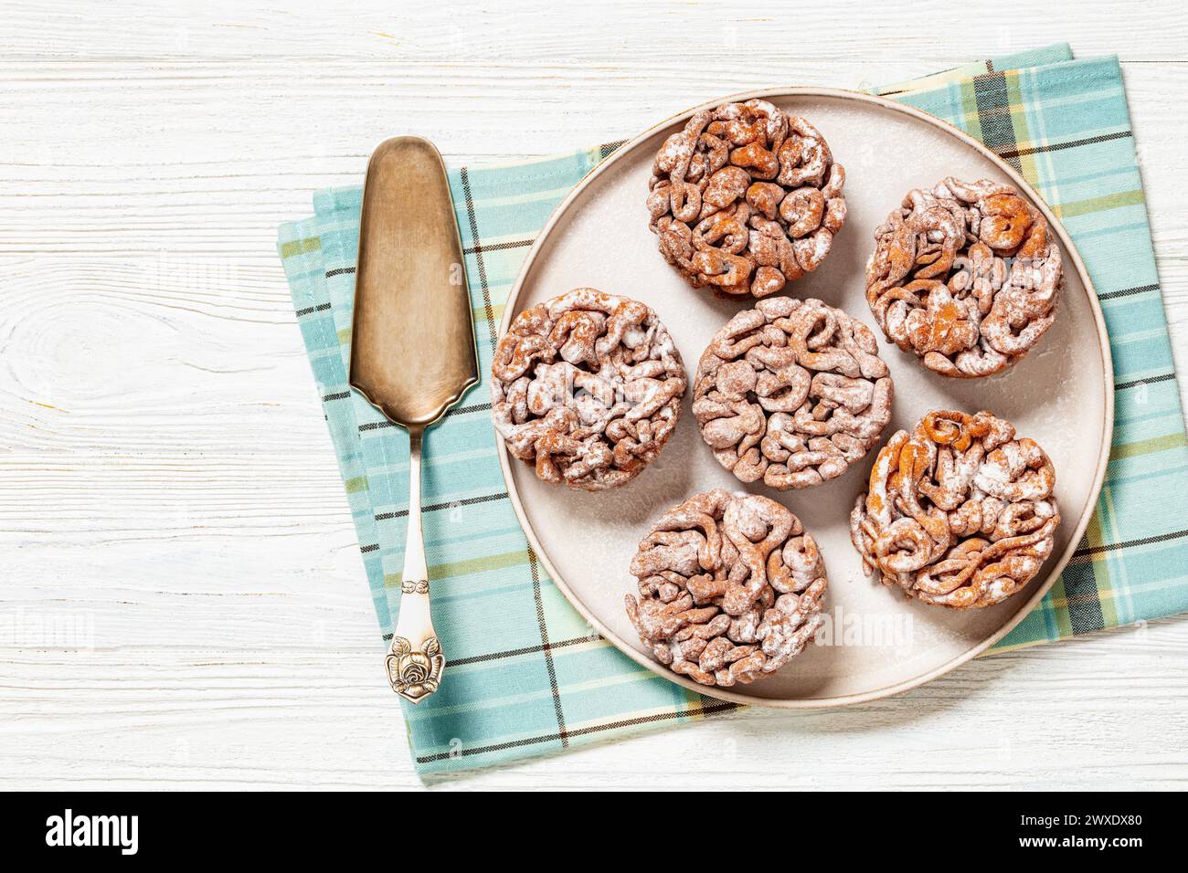 Tippaleipa, finnischer Mai Tag Trichterkuchen frittiert und mit Puderzucker bestäubt für einen süßen Teller auf weißem Holztisch mit Kuchenschaufel, Horizo Stockfoto